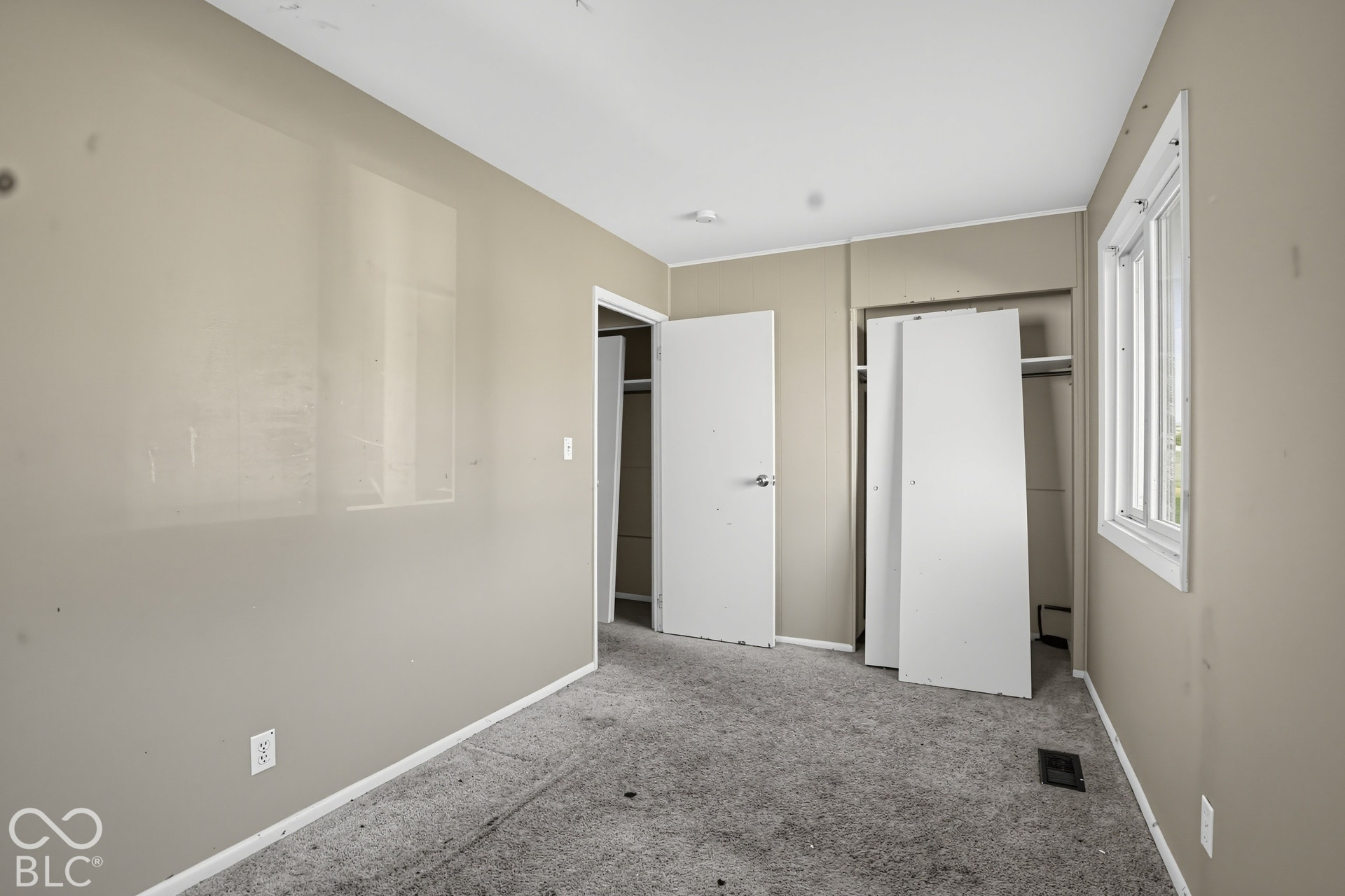 Interior room featuring neutral wall paint, carpeted flooring, a closet with shelving, and a double-pane window