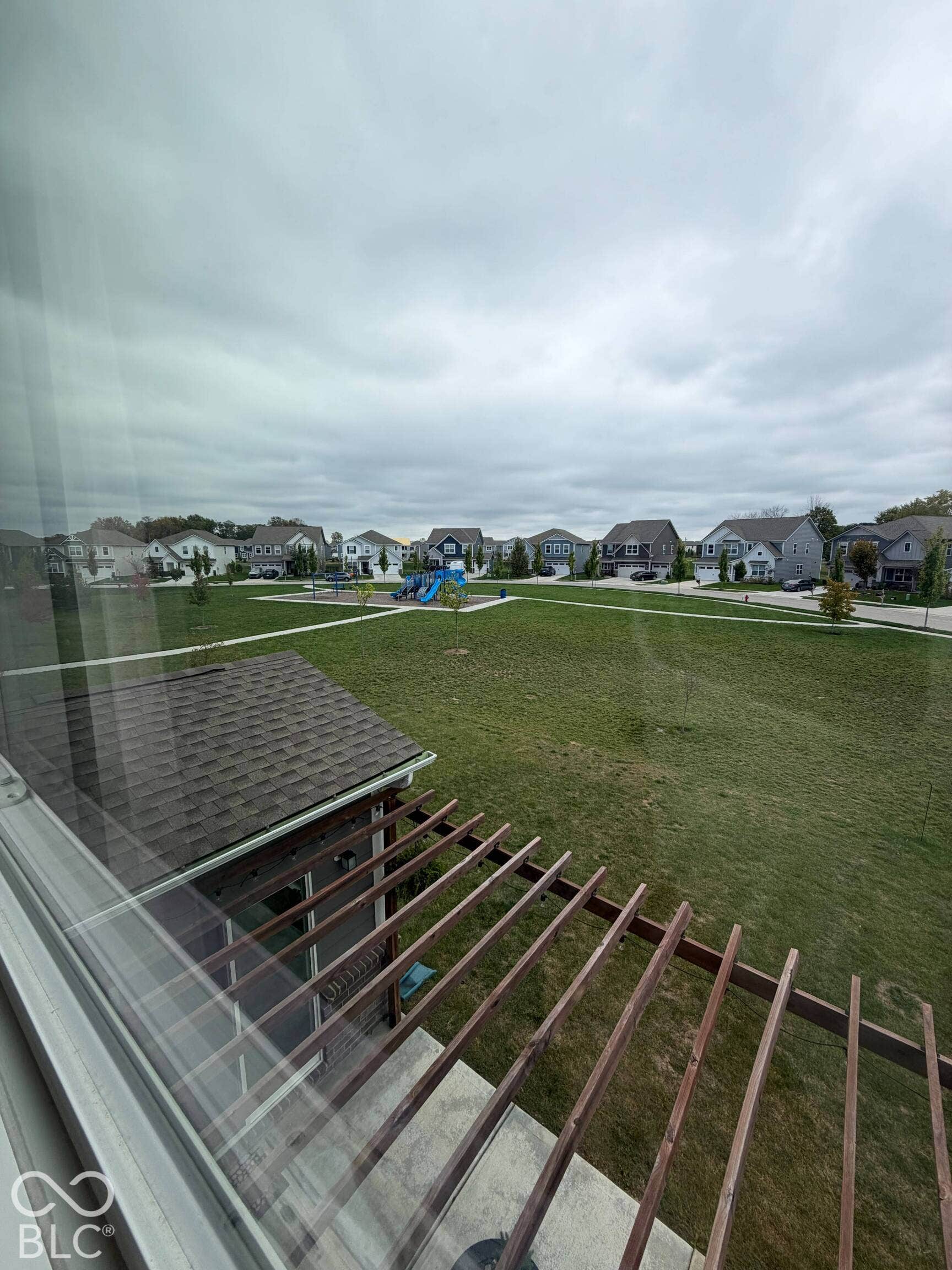 Extensive green space with playground equipment, surrounded by residential properties, and a partial pergola structure