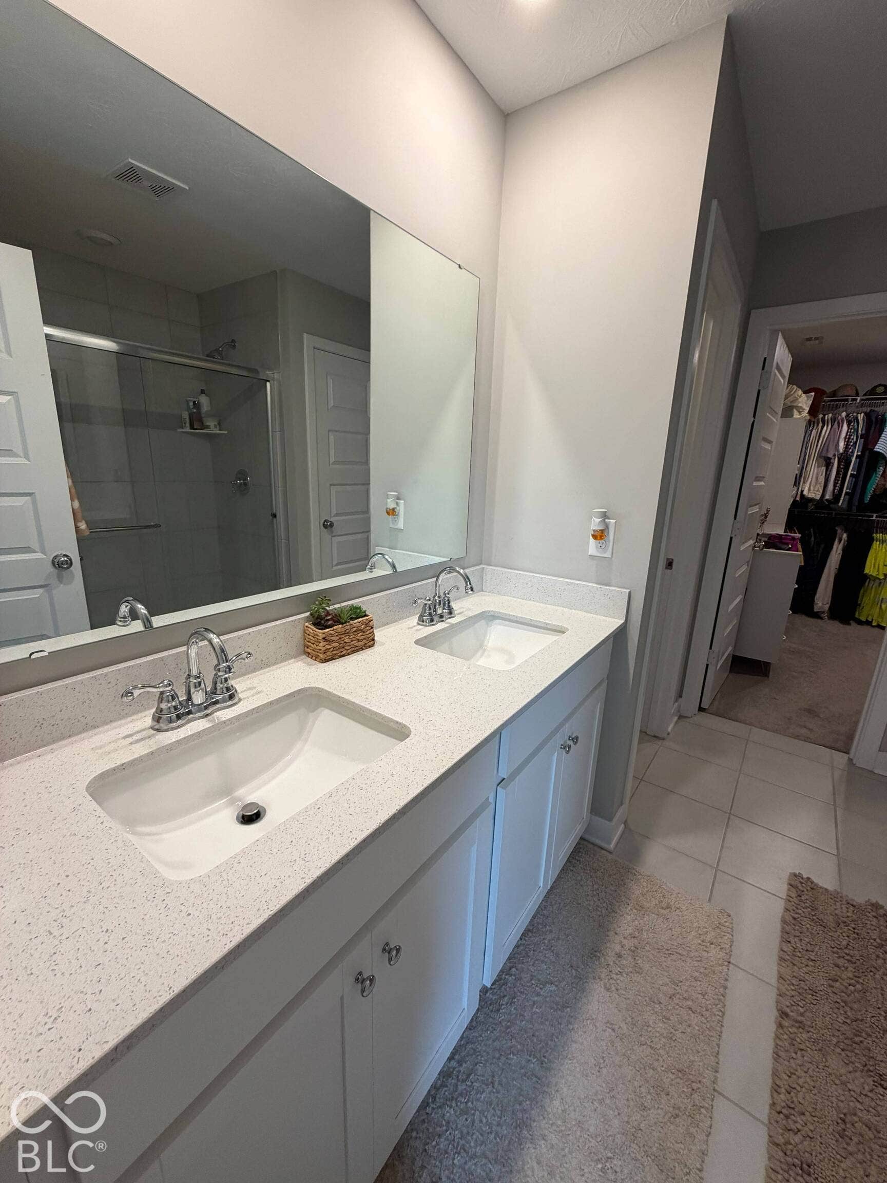 Dual vanity with integrated sinks, speckled countertop, chrome fixtures, and white cabinetry