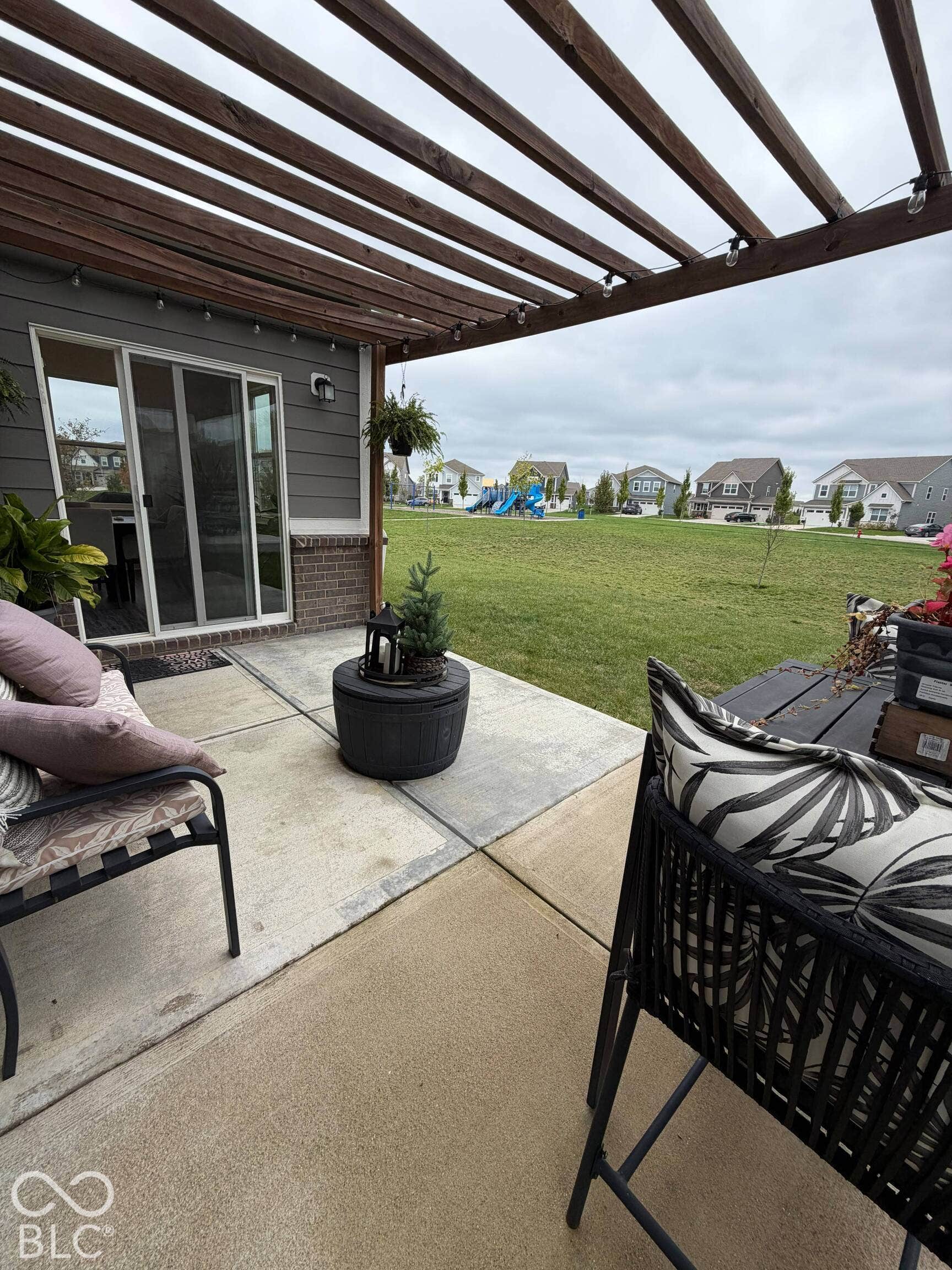 Rear patio with a wood pergola, string lighting, and direct access to a grassy expanse