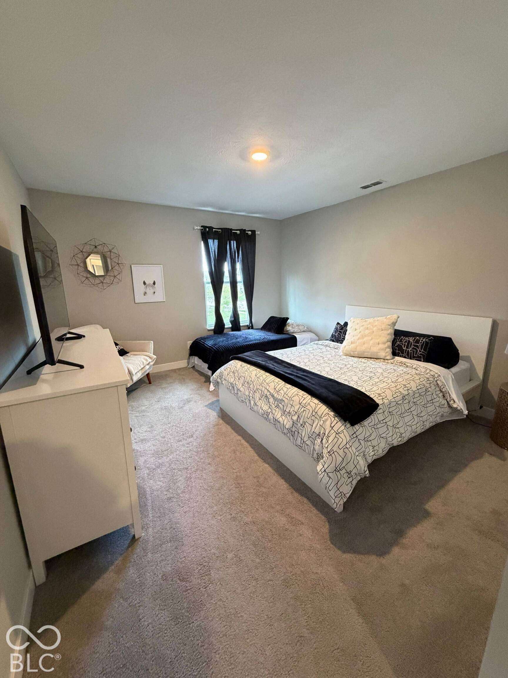 Carpeted flooring, neutral wall paint, and a window with dark curtains