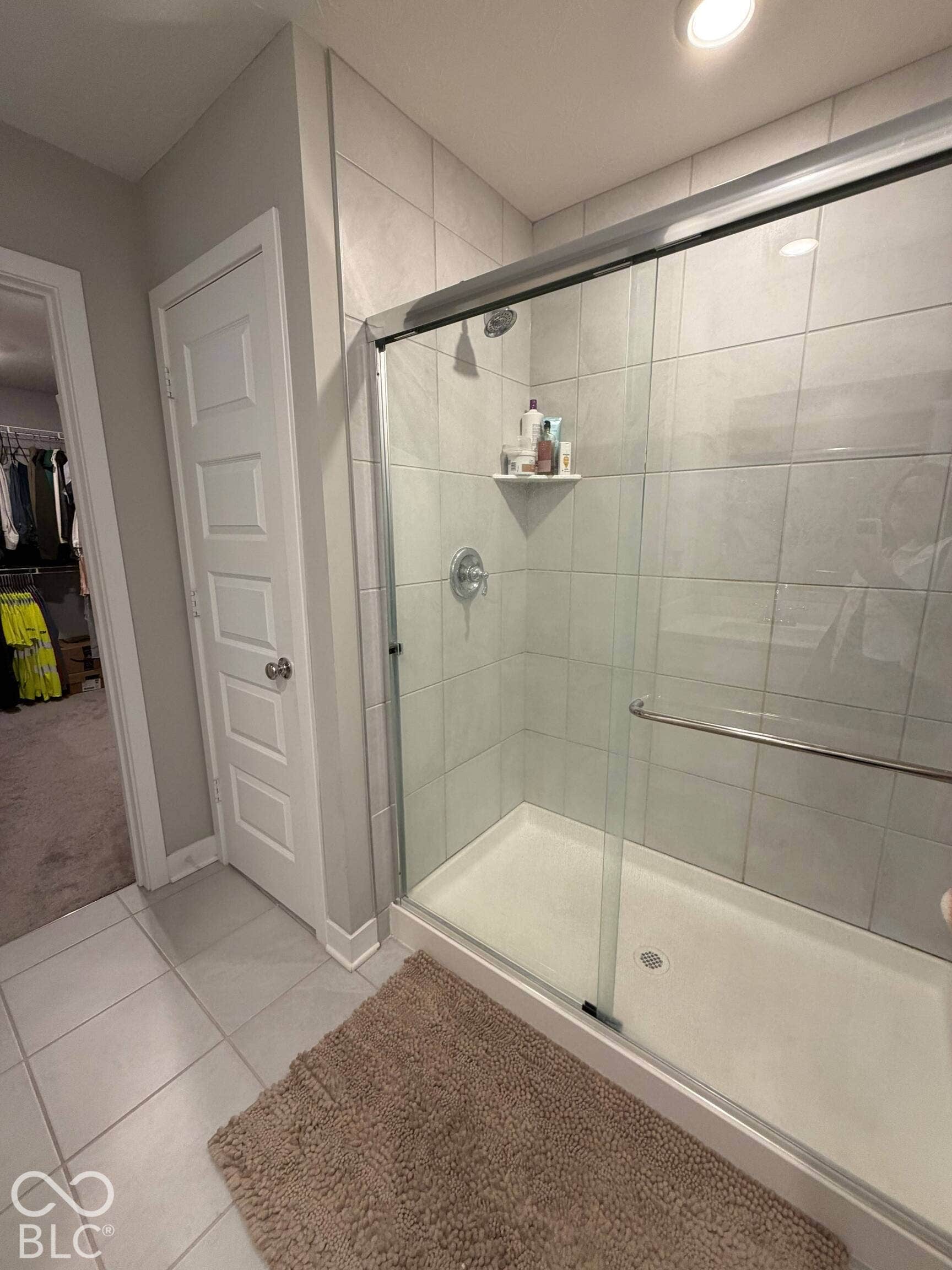 Tiled shower with sliding glass door enclosure and built-in shelving
