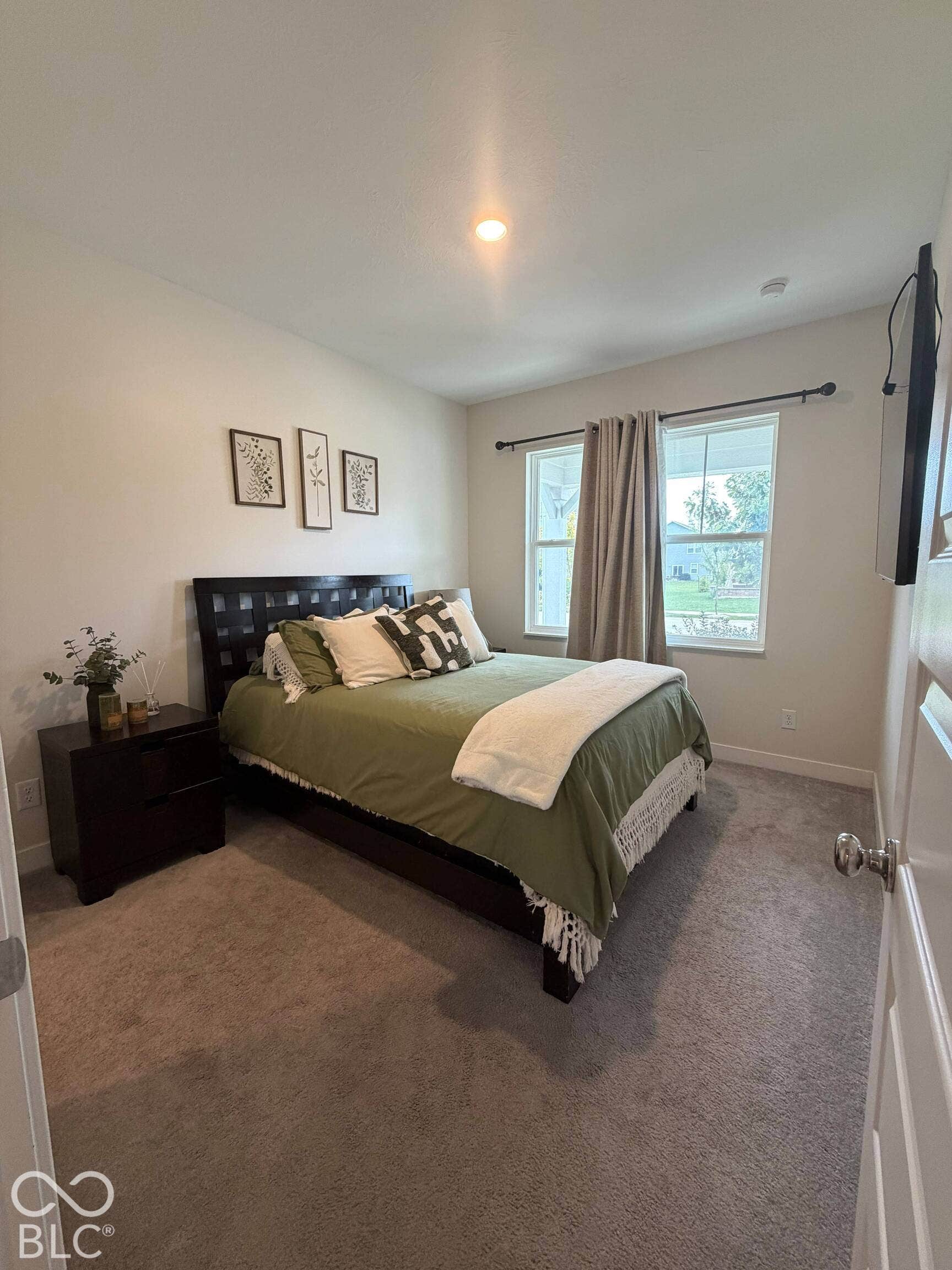Recessed ceiling light, dual pane windows, dark wood-finish nightstand, and gray carpet flooring