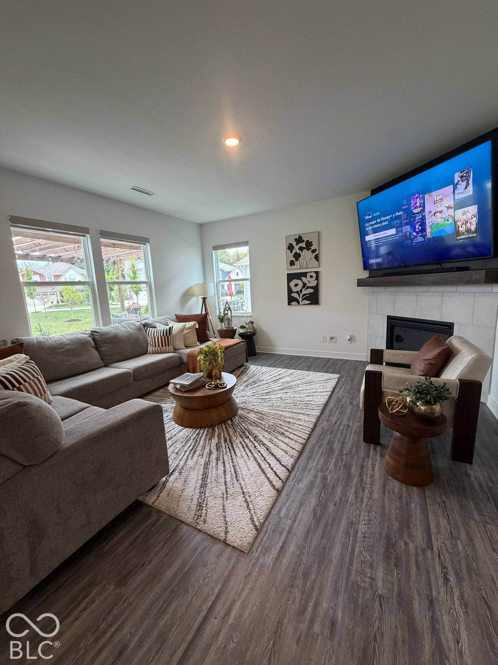Wood-finish flooring throughout, multiple windows providing natural light, and a fireplace with a wood mantel