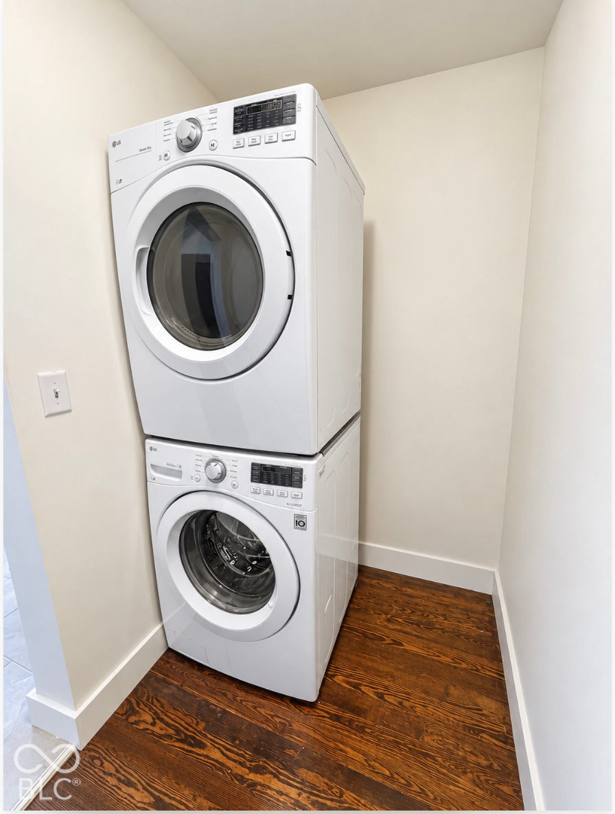 Stacked laundry appliances with wood-finish flooring