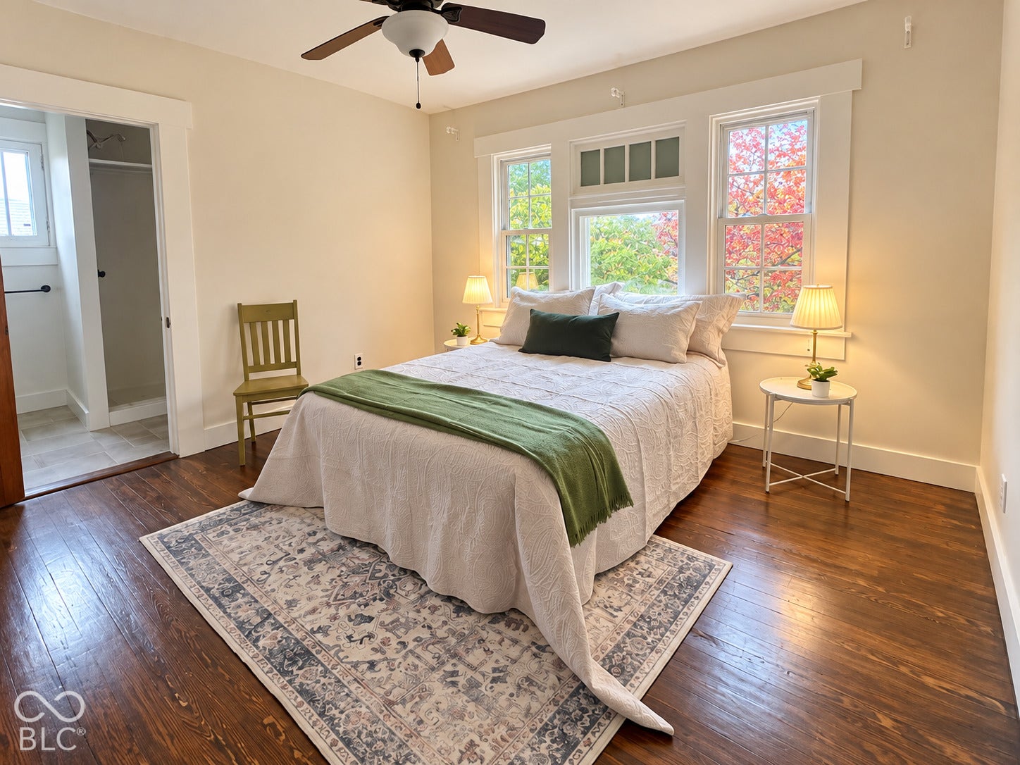 Wood-finish flooring, white window casing with transom detailing, and a ceiling fan with a central light fixture
