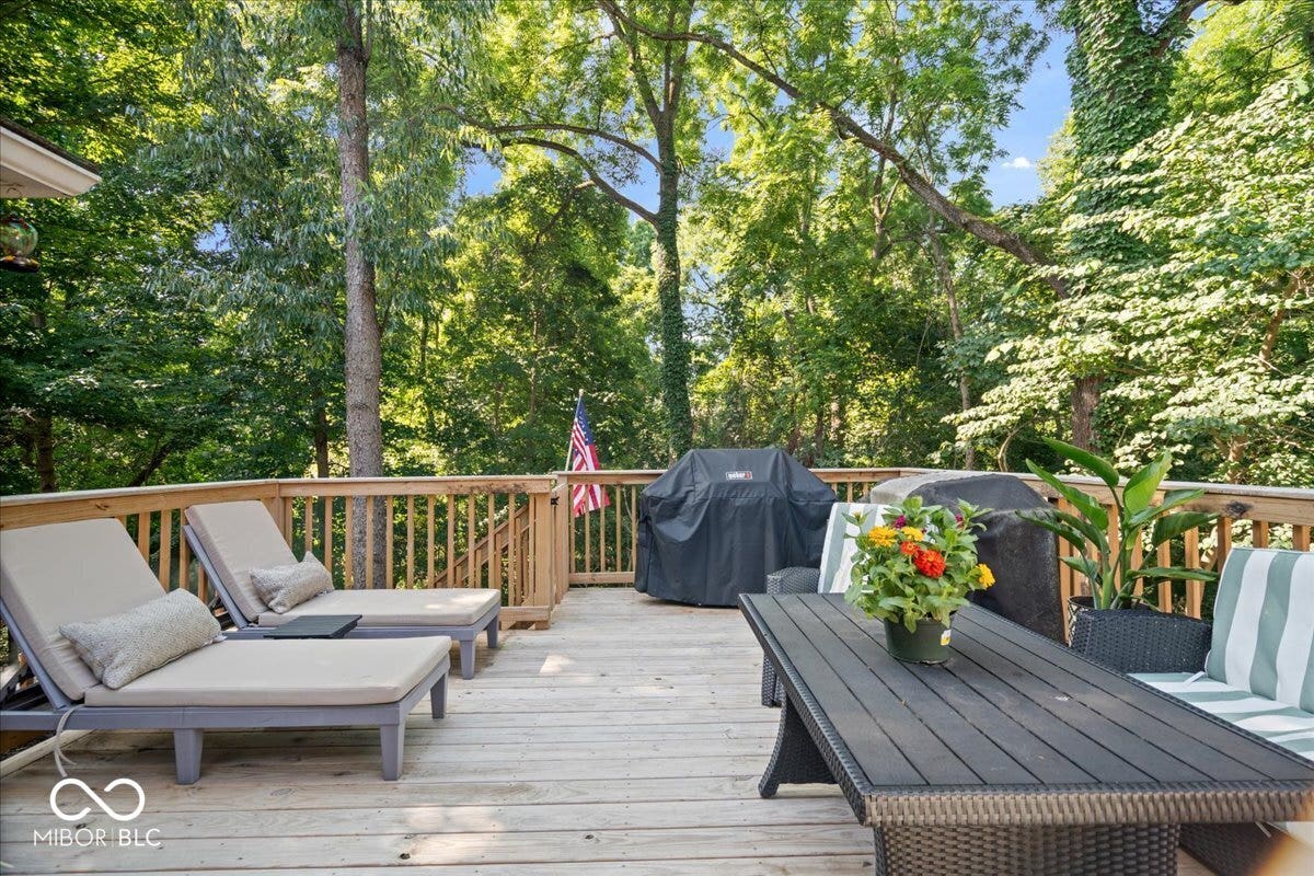 Expansive wood deck with a natural wood railing, surrounded by mature trees