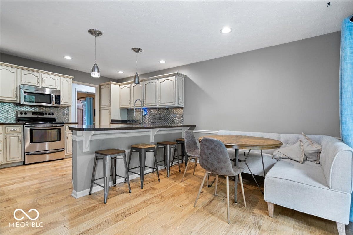 Kitchen featuring wood flooring, a breakfast bar, stainless steel appliances, and backsplash