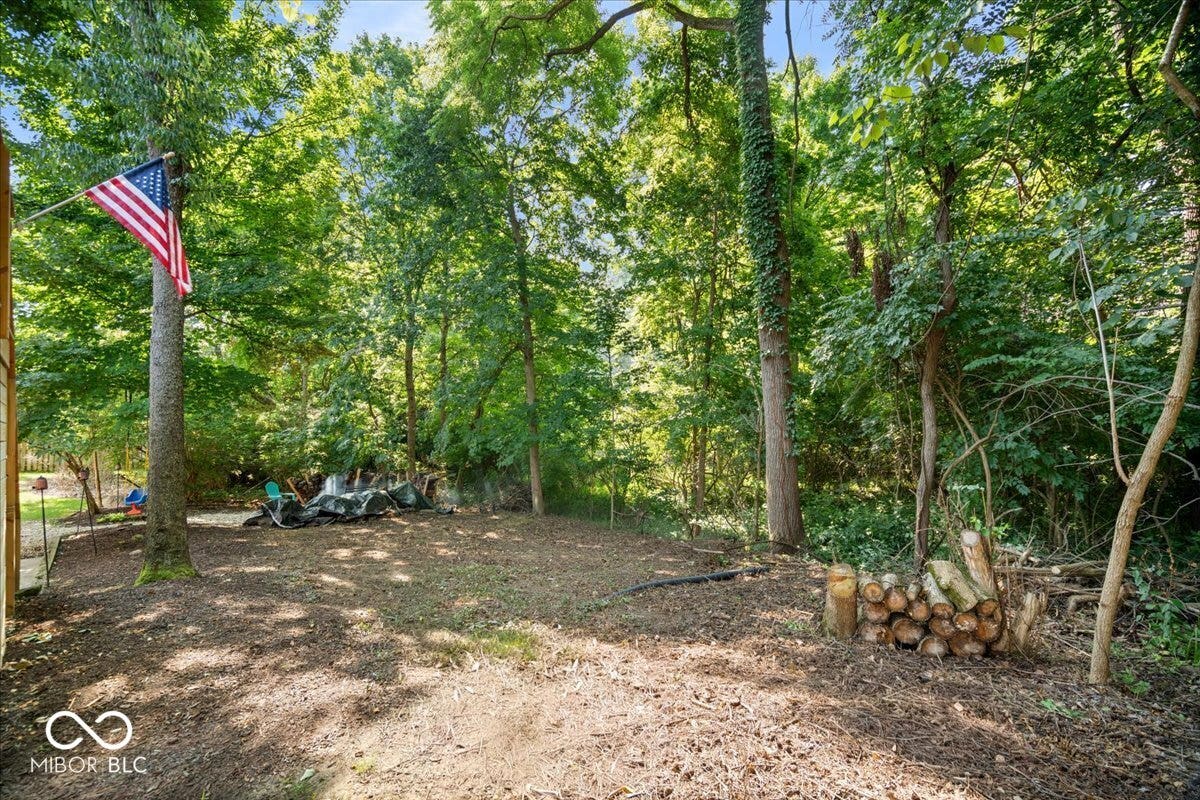 Expansive wooded lot featuring mature trees and a cleared area offering a blank canvas for future homeowners to create their ideal landscaping.