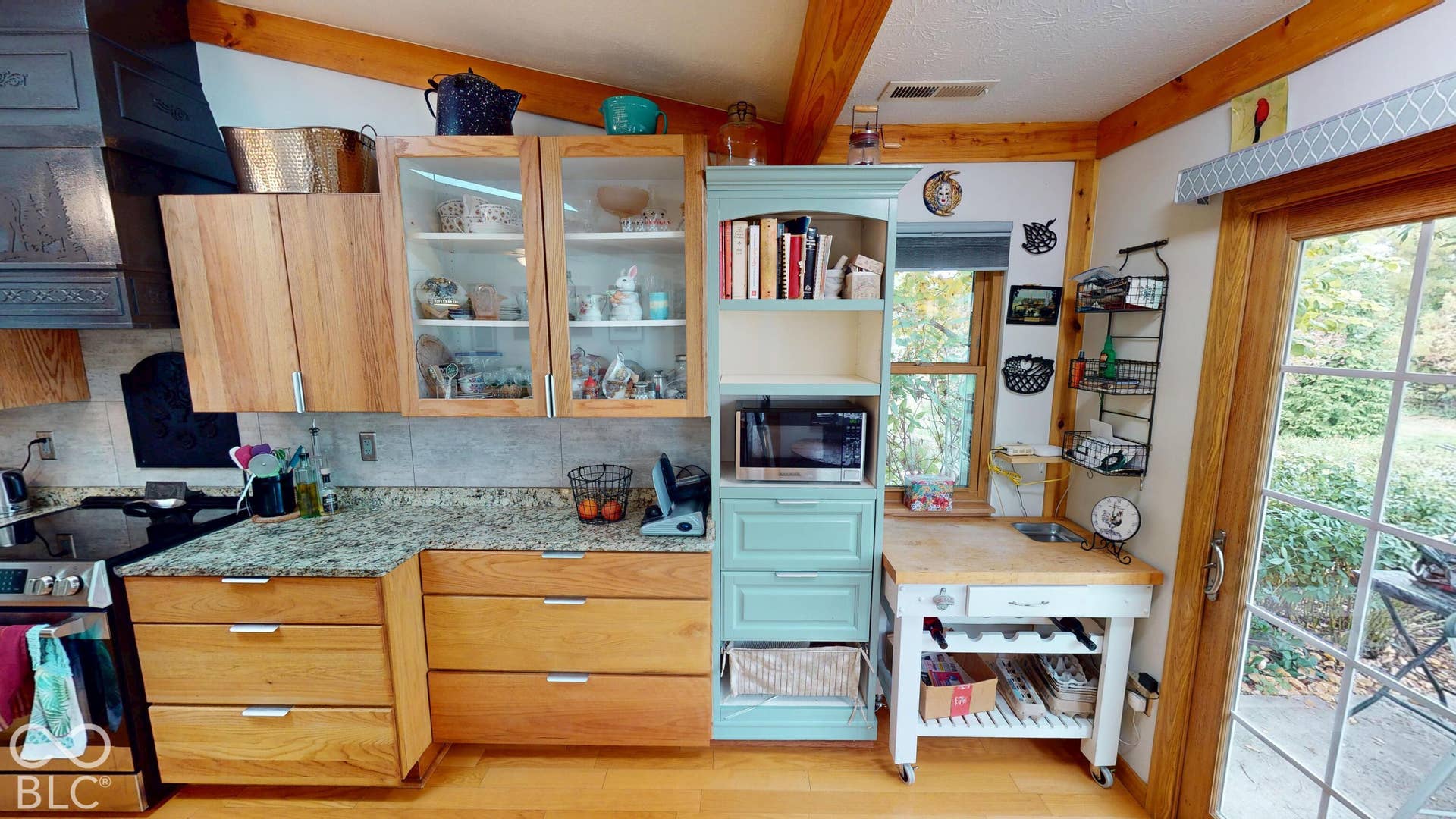 Kitchen featuring wood-finish cabinetry, granite countertops, glass-front upper cabinets, a built-in oven, and exposed wood beams