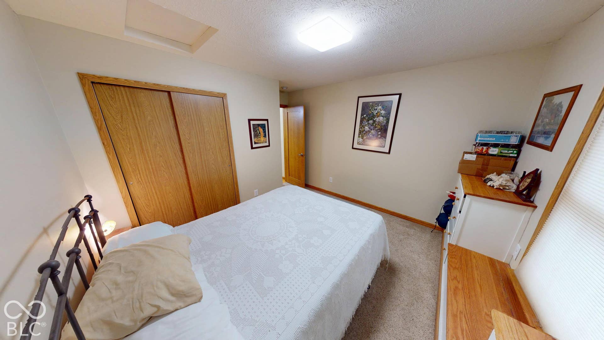 Bedroom #2 =Neutral wall paint, wood-finish bi-fold closet doors, carpeted flooring, built-in window bench, and an overhead light fixture
