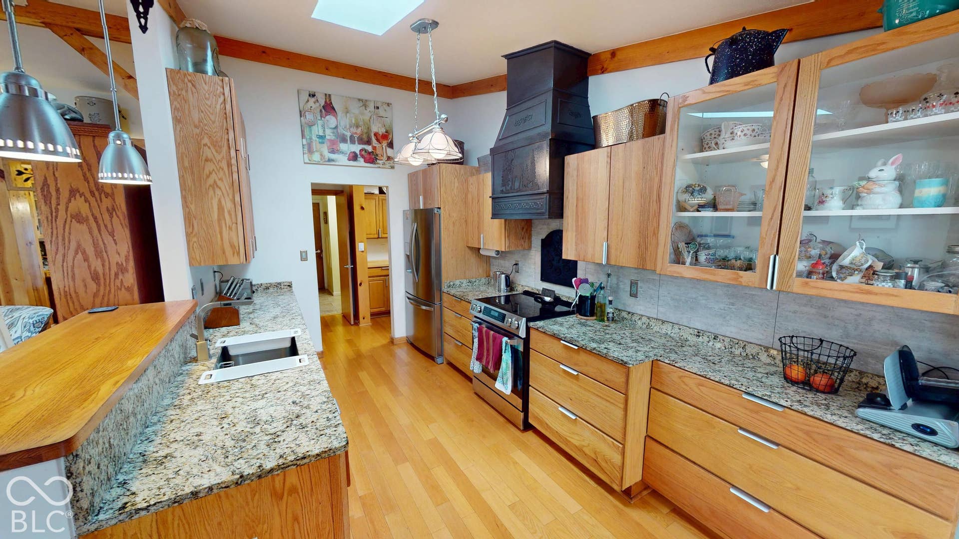Kitchen with wood-finish flooring, wood cabinetry, stone countertops, and a skylight