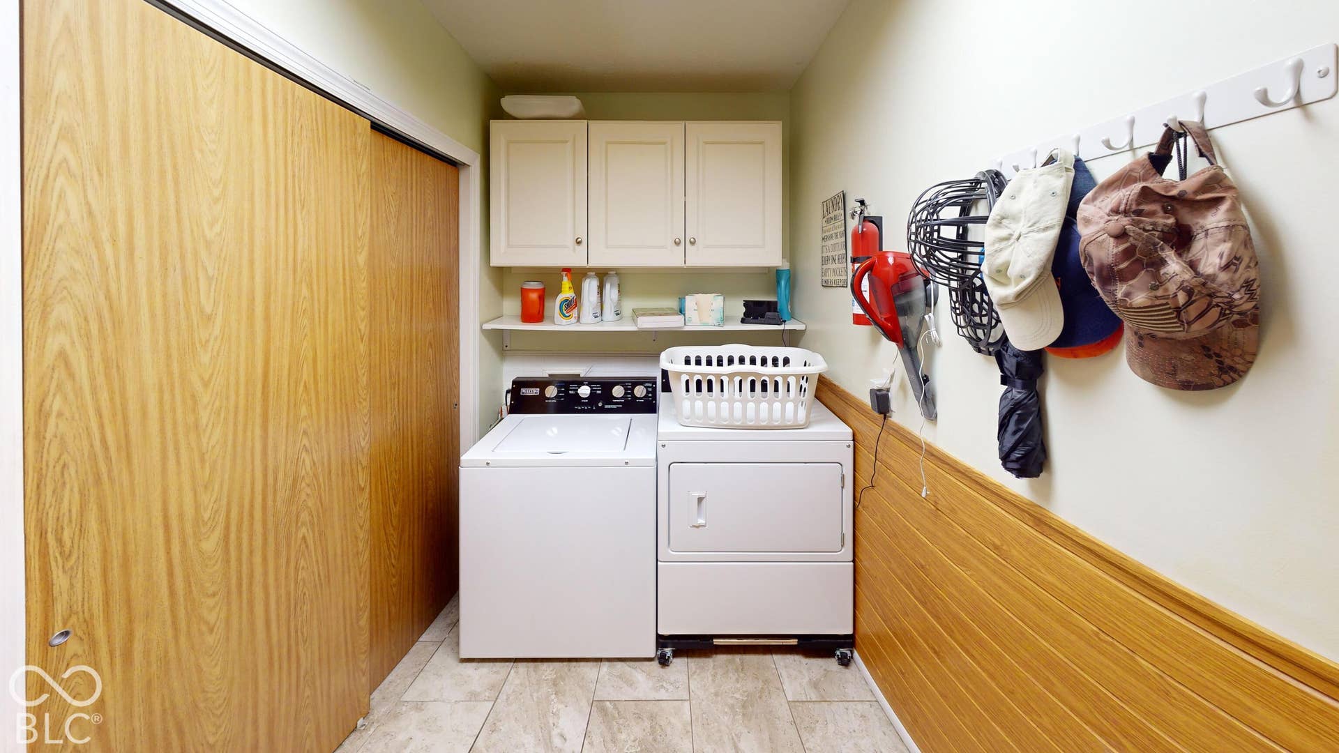 Wood-finish sliding closet doors, built-in upper cabinetry, wall-mounted shelving, and wood-finish paneling