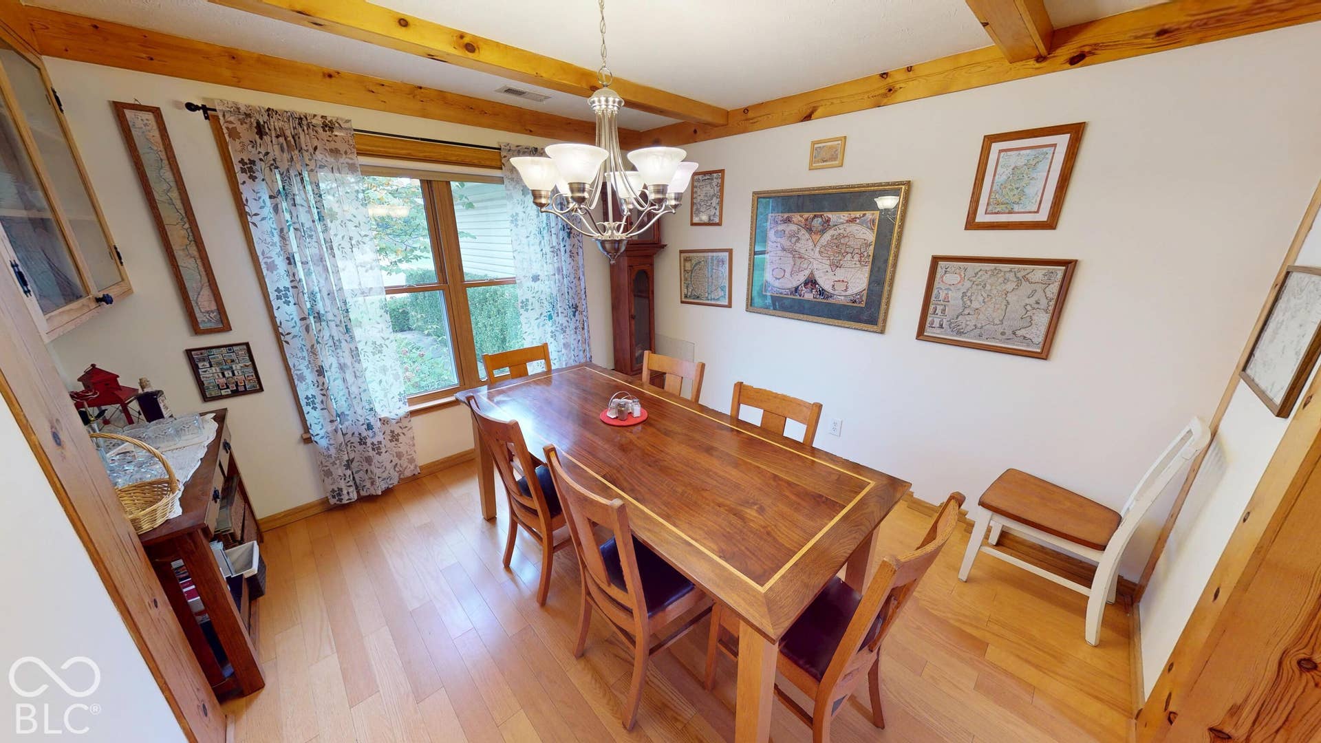Exposed wood ceiling beams, hardwood flooring, and a multi-pane window