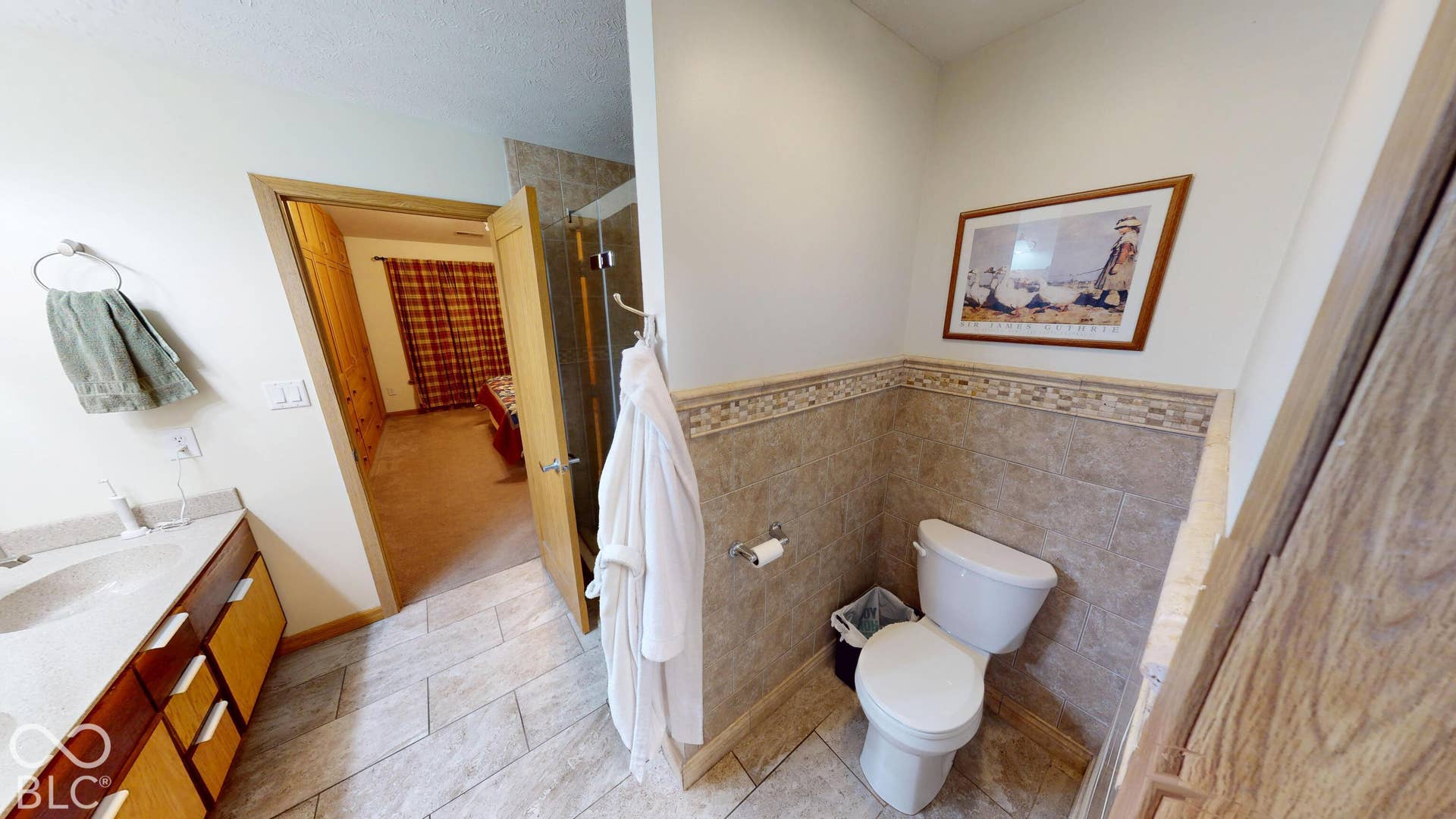 Bathroom featuring a single vanity, tiled flooring, tiled shower, and a toilet