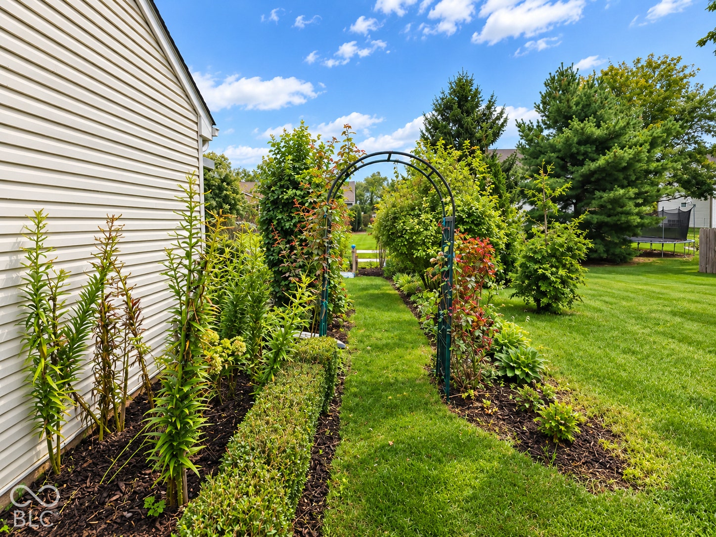 Expansive lawn with manicured landscaping, mature trees, and an ornamental garden archway