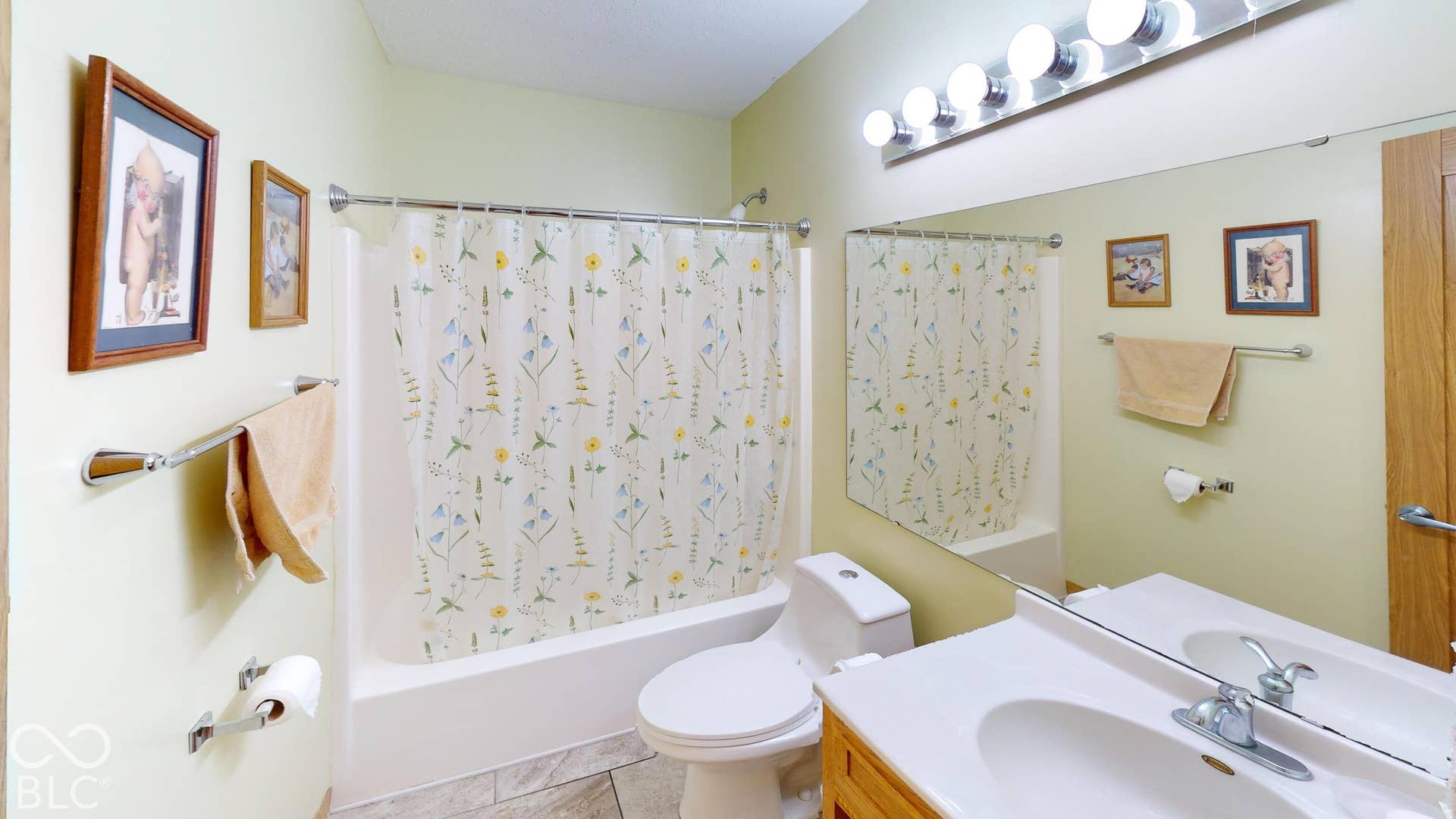 Full vanity mirror, integrated vanity lighting, single basin sink, white toilet, and a white tub with shower