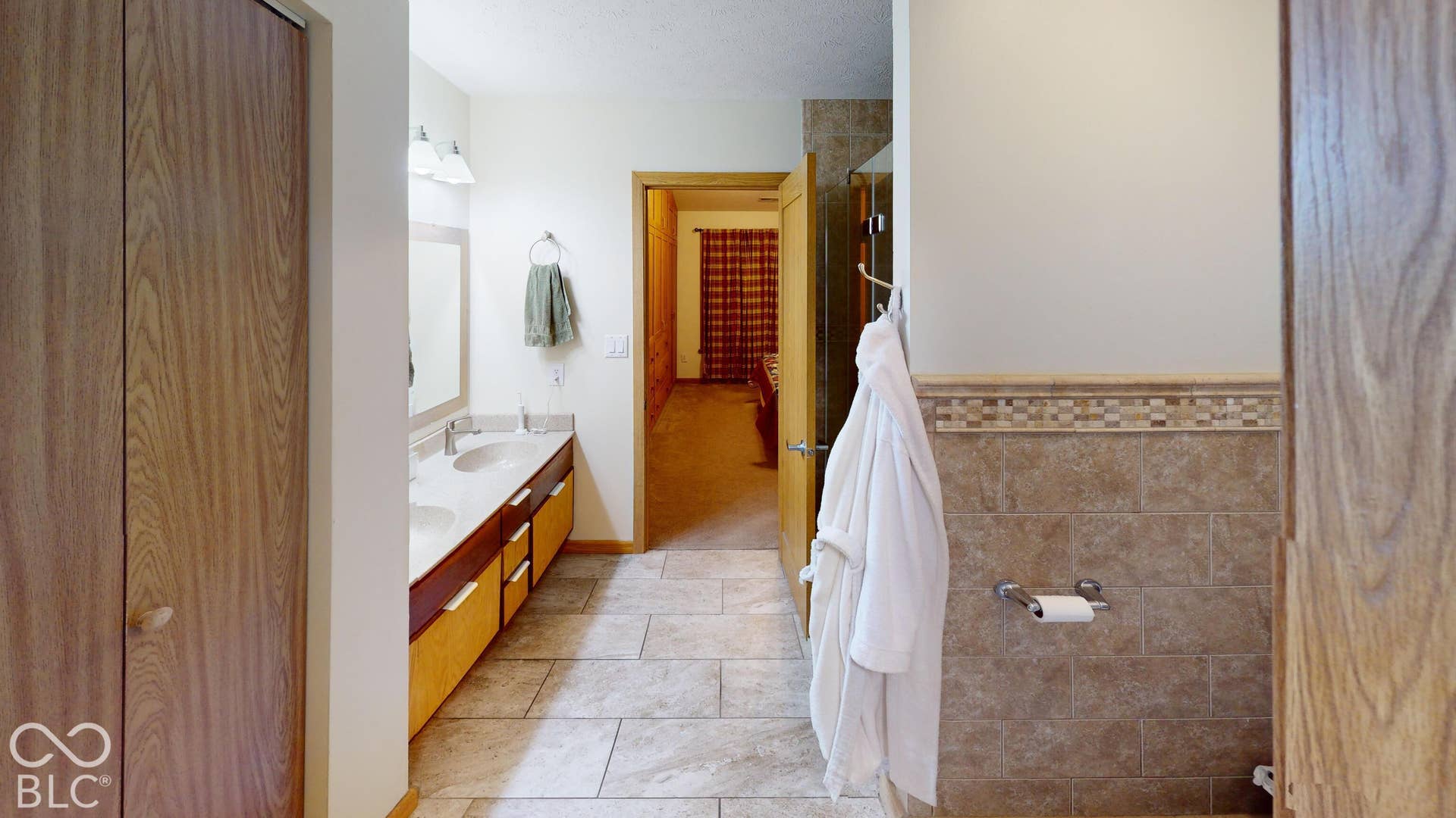 Dual vanity with undermount sinks, tile flooring, and a tiled shower enclosure
