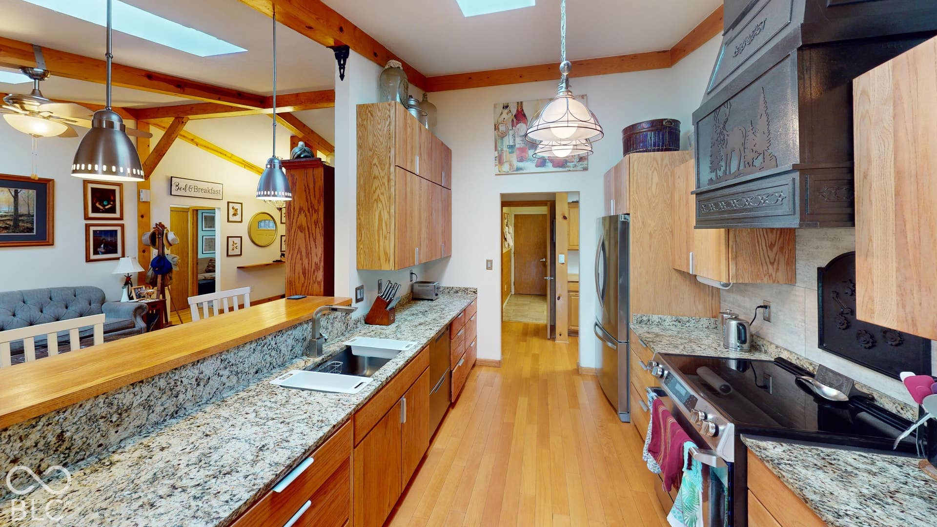 Kitchen featuring wood-finish cabinetry, stone countertops, stainless steel appliances, and skylights