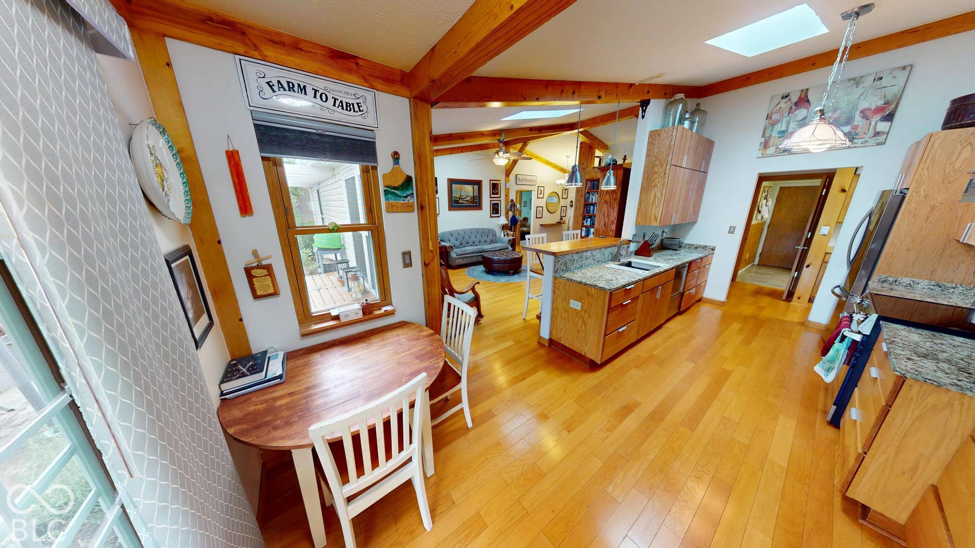 Hardwood flooring, wood-finish exposed beams, skylight, and a kitchen island with a built-in sink