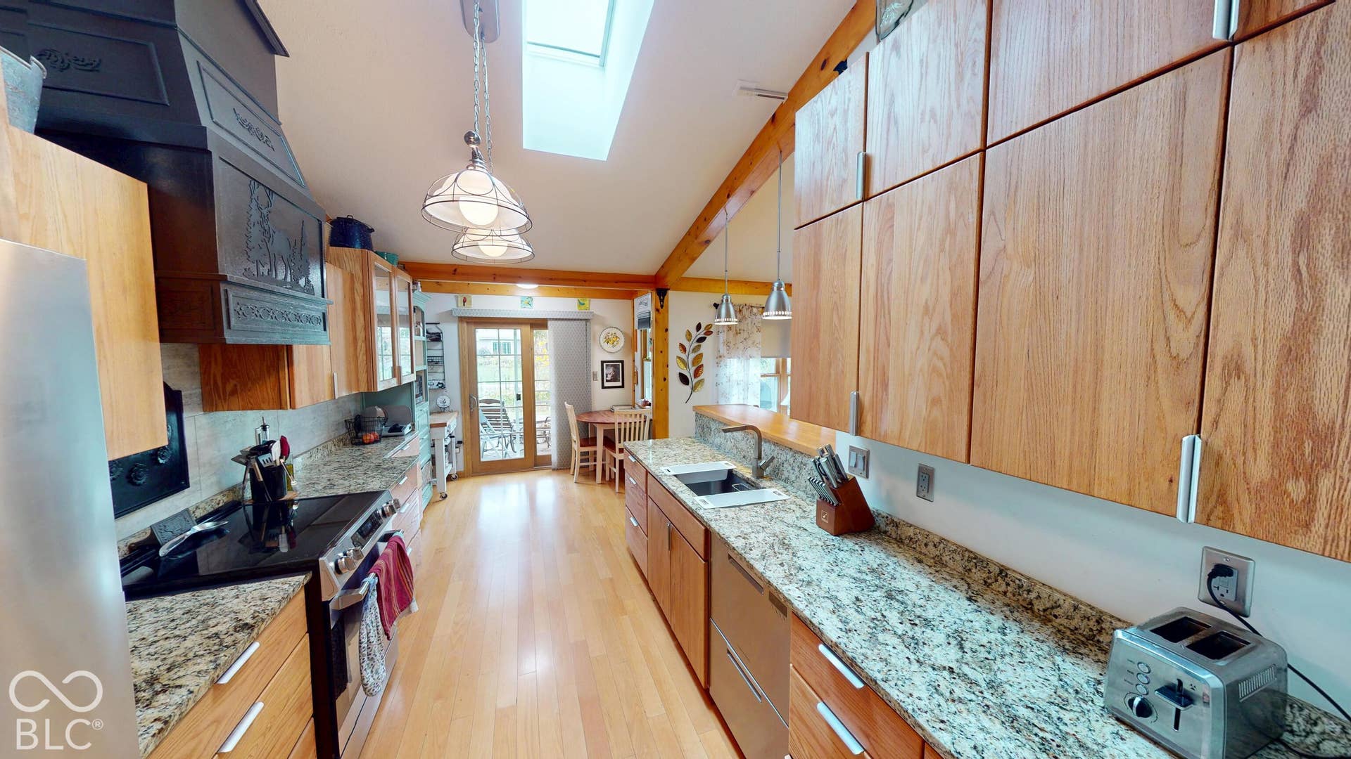 Kitchen featuring exposed wood beams, wood-finish cabinetry, granite countertops, and wood-finish flooring
