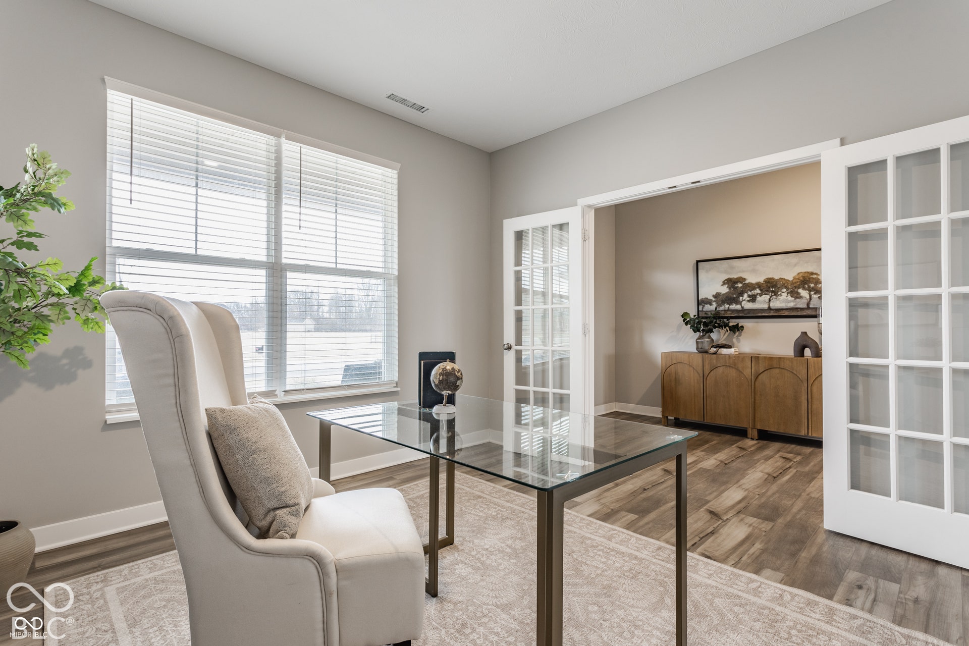 Room featuring wood-finish flooring, white French doors with glass panes, and a large window with horizontal blinds