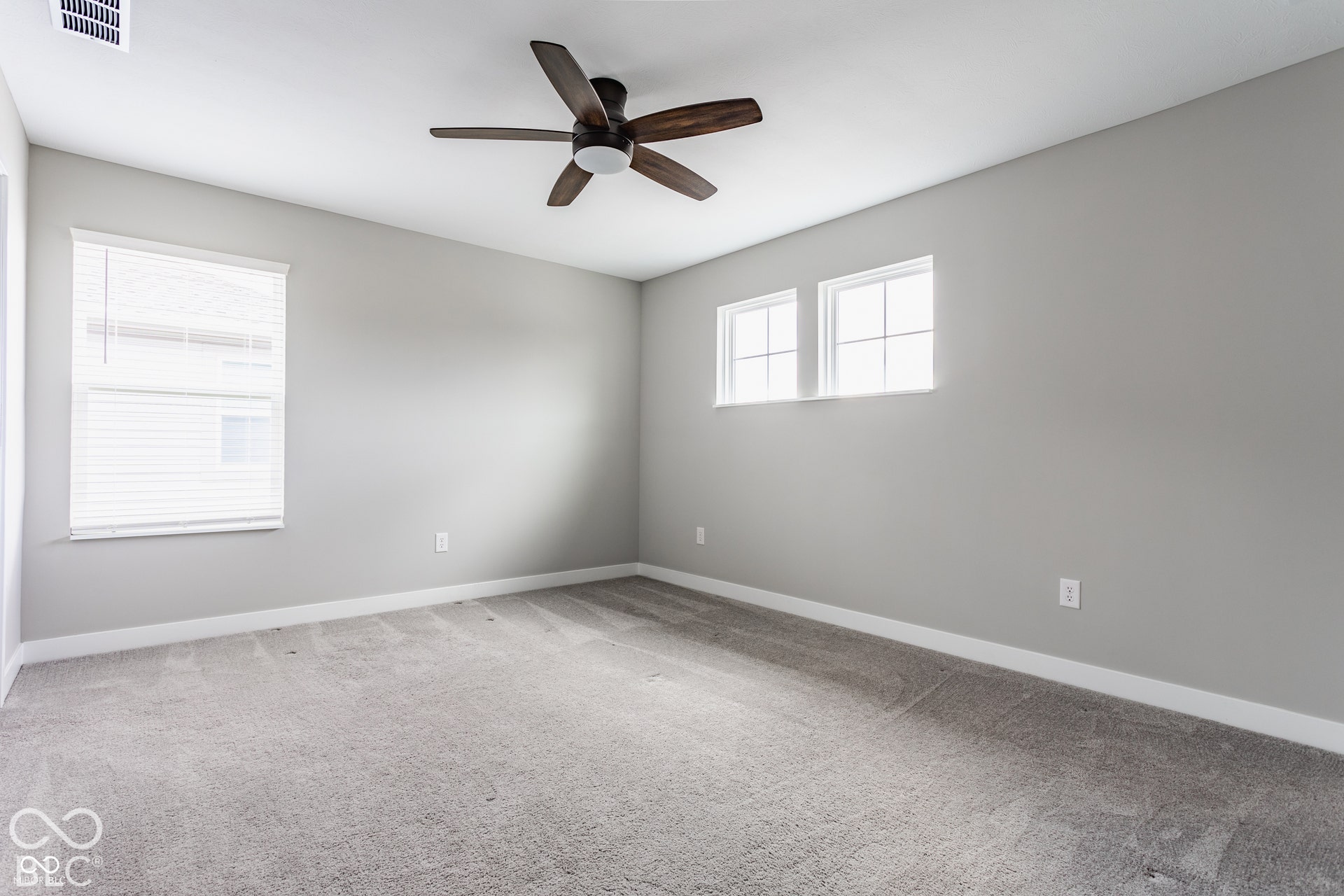 Neutral-toned interior space featuring wall-to-wall carpeting, a five-blade ceiling fan, and multi-pane windows