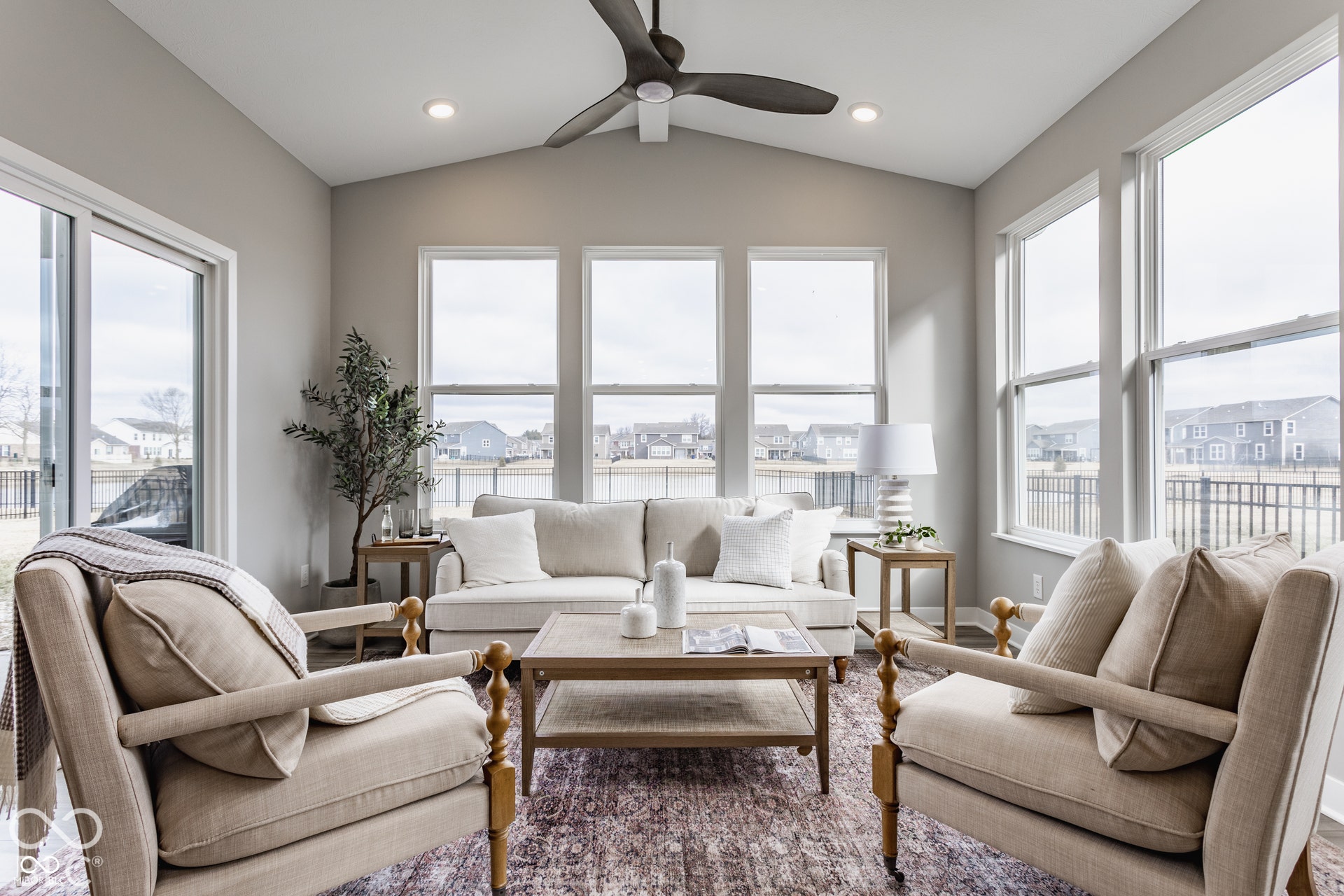 Sunroom featuring vaulted ceilings, oversized windows, wood-finish flooring, a matte black ceiling fan, and recessed lighting