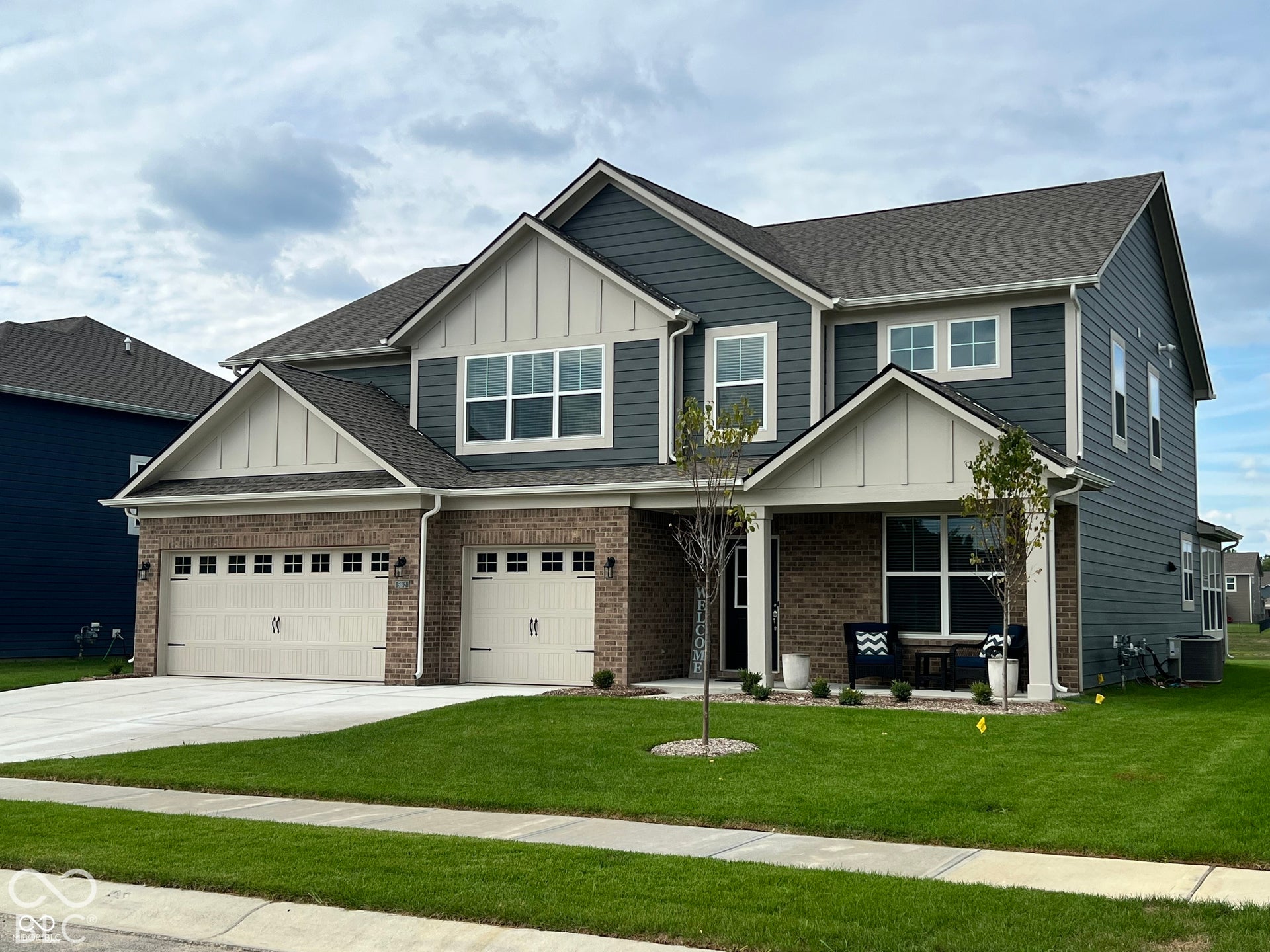 Multi-gabled exterior featuring a combination of horizontal lap siding, vertical board-and-batten accents, and brick masonry, complemented by a multi-car garage and a covered front entry