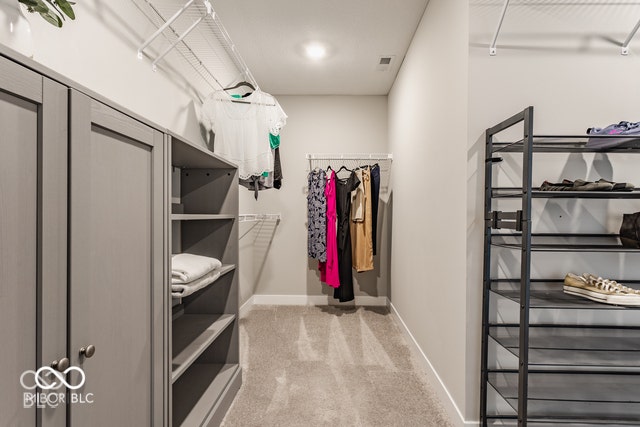 Walk-in closet featuring grey shaker-style cabinetry, open shelving units, and wire garment racking