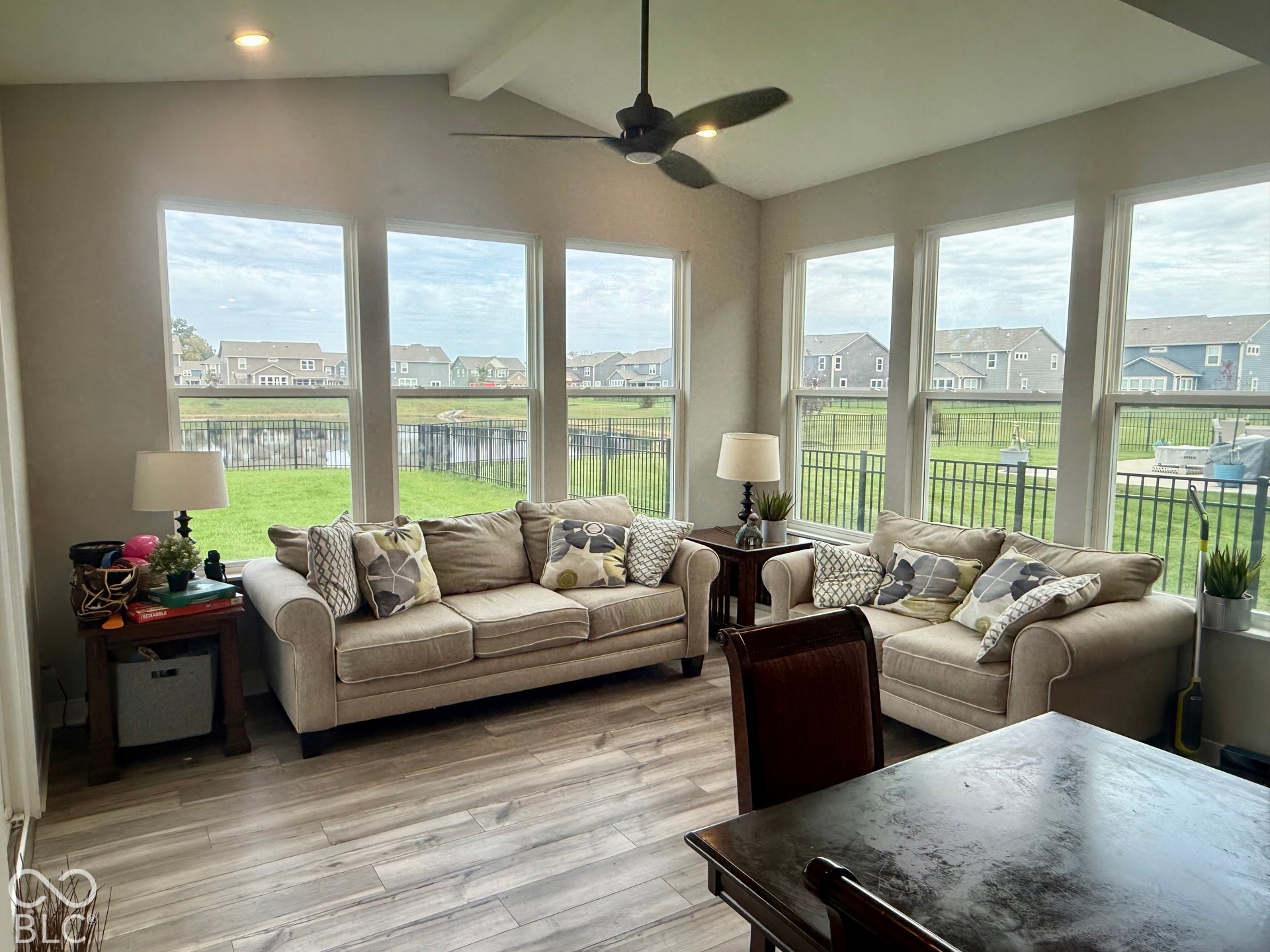 Vaulted ceiling, wood-finish flooring, recessed lighting, ceiling fan with integrated light, and large windows with water-facing orientation