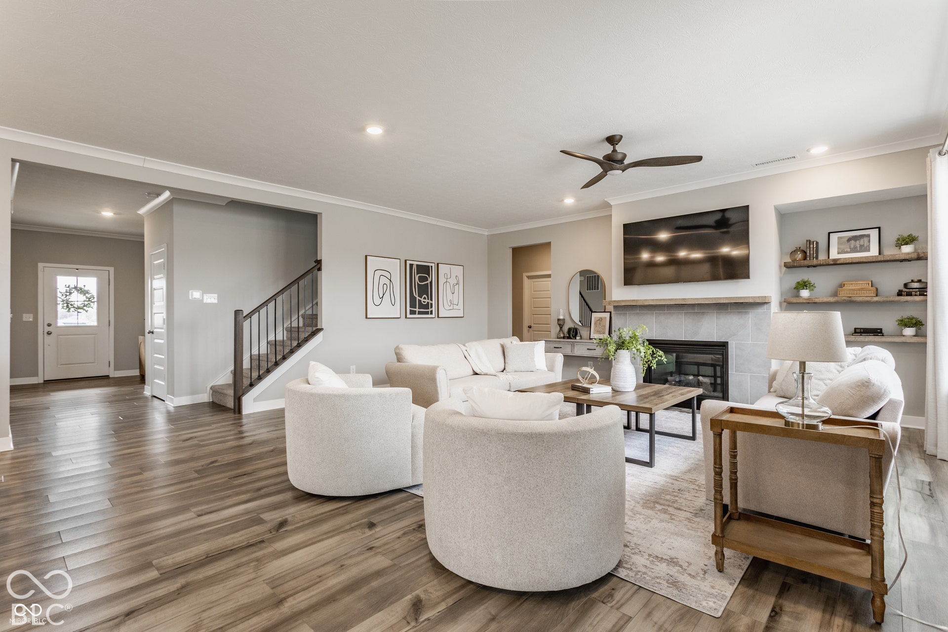 Open floor plan featuring wood-finish flooring, recessed lighting, fireplace with stone surround, wood-finish mantel, and custom built-in shelving