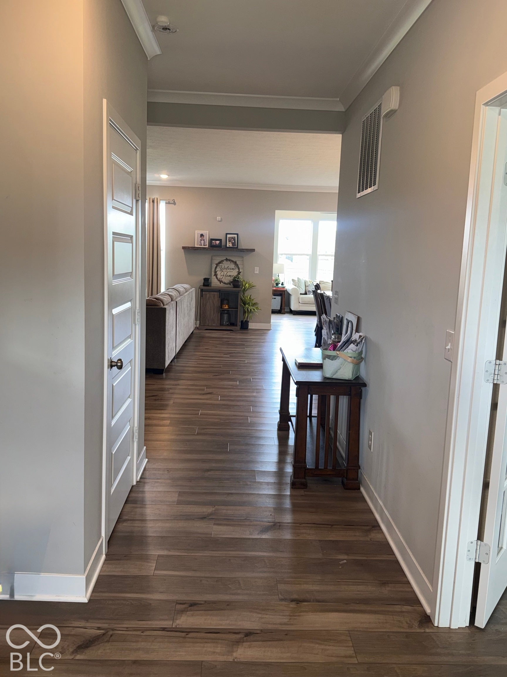 Hallway featuring wood-finish flooring, crown molding, and multi-panel interior doors