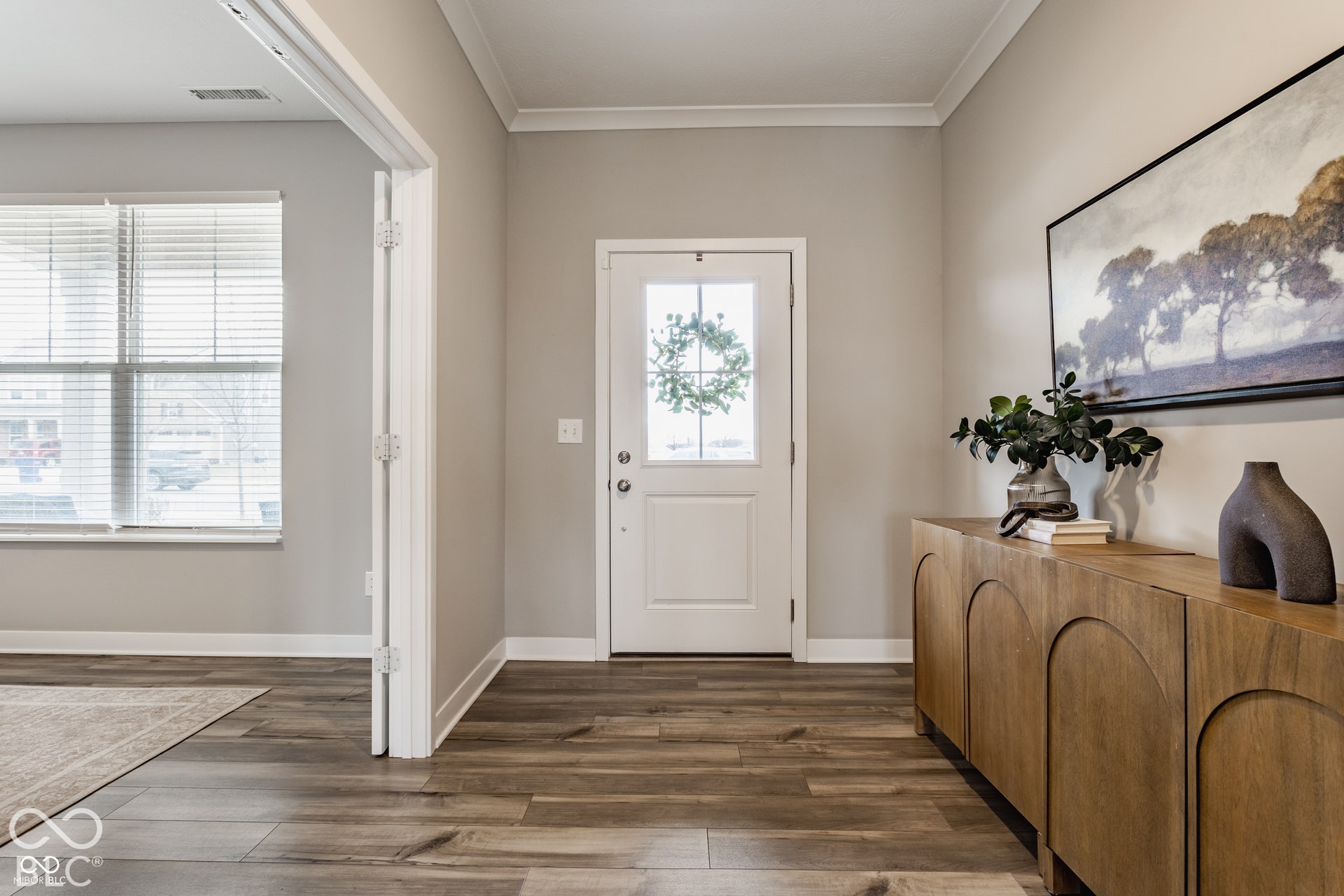 Entryway featuring wood-finish flooring, neutral wall paint, white crown molding, and a paneled door with an integrated glass insert