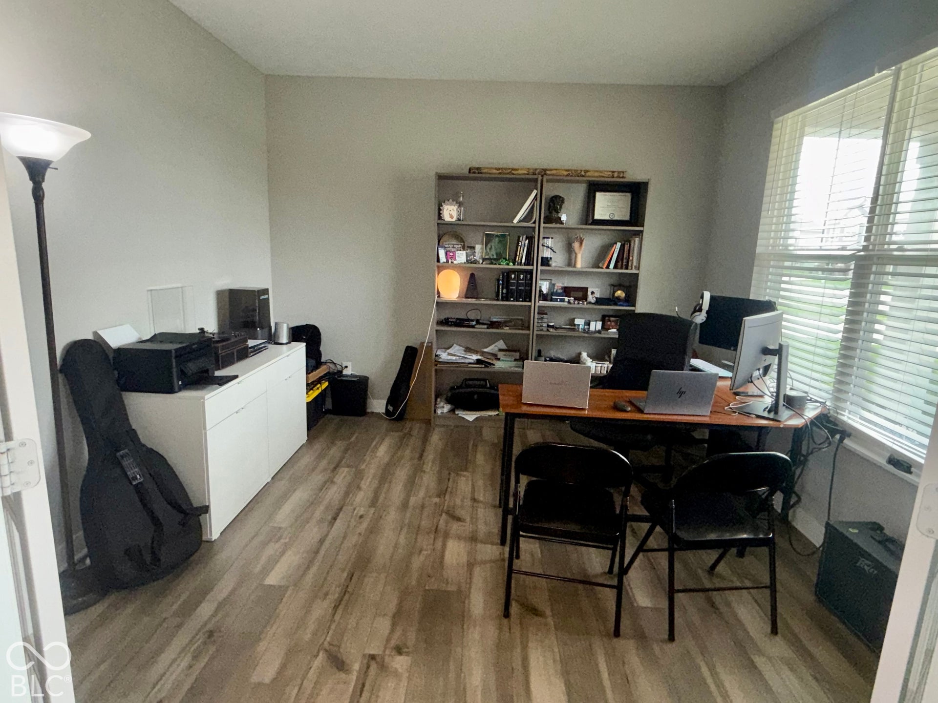 Room featuring wood-finish flooring, neutral wall paint, and a window with horizontal blinds