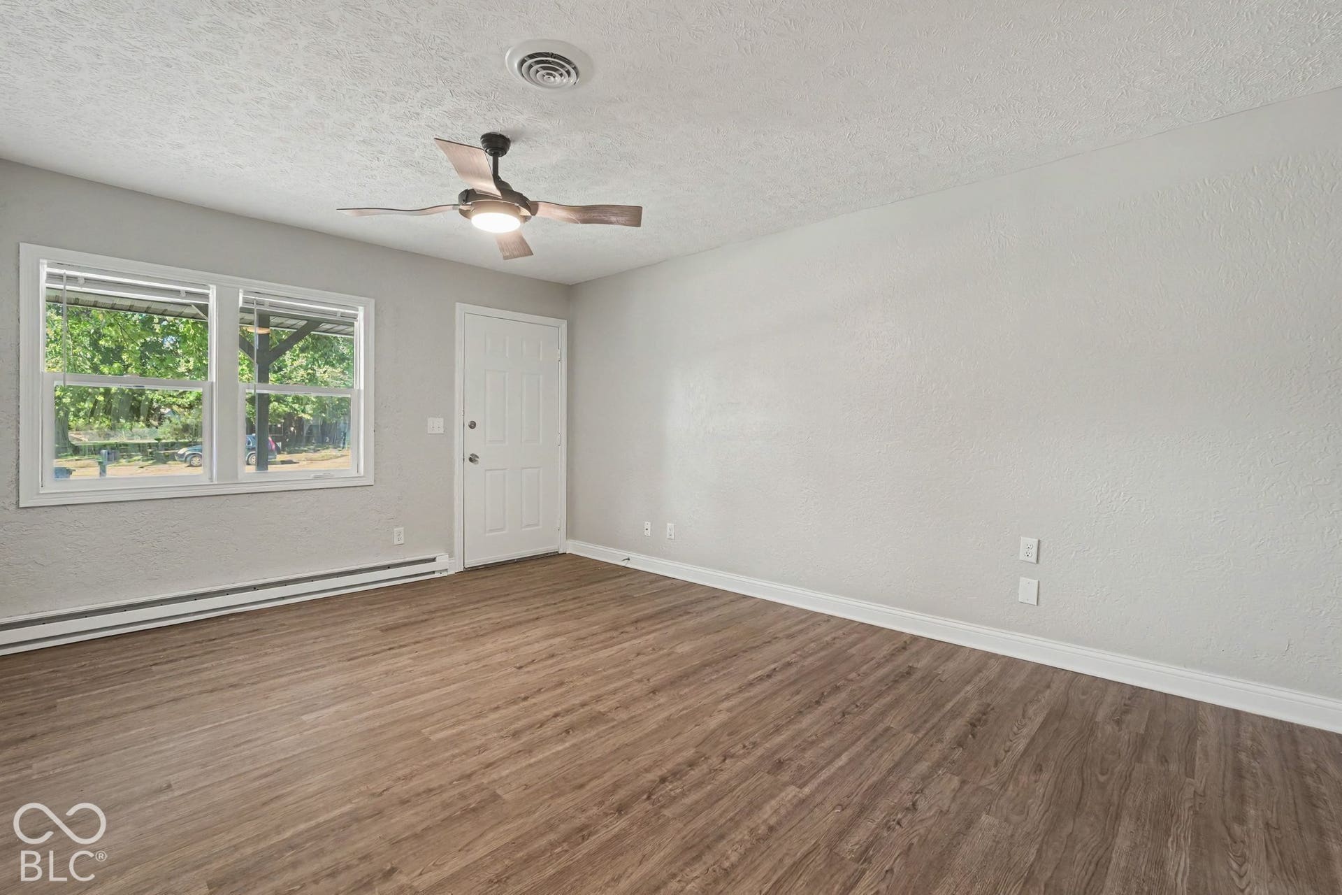 Wood-finish flooring, ceiling fan, white paneled door, and dual pane windows