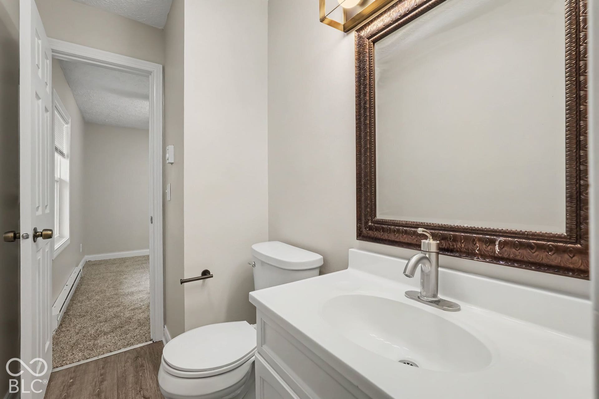 White vanity with integrated sink, brushed nickel faucet, and framed mirror