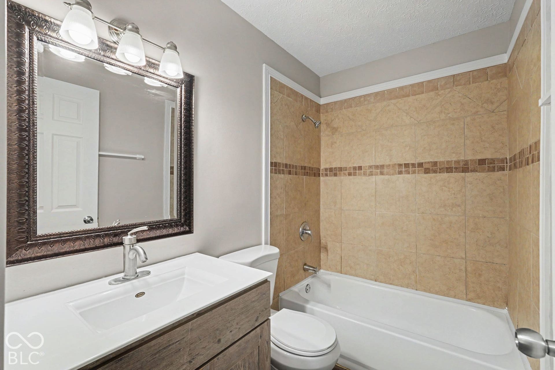 Vanity with integrated sink, brushed nickel faucet, and ornamental framed mirror