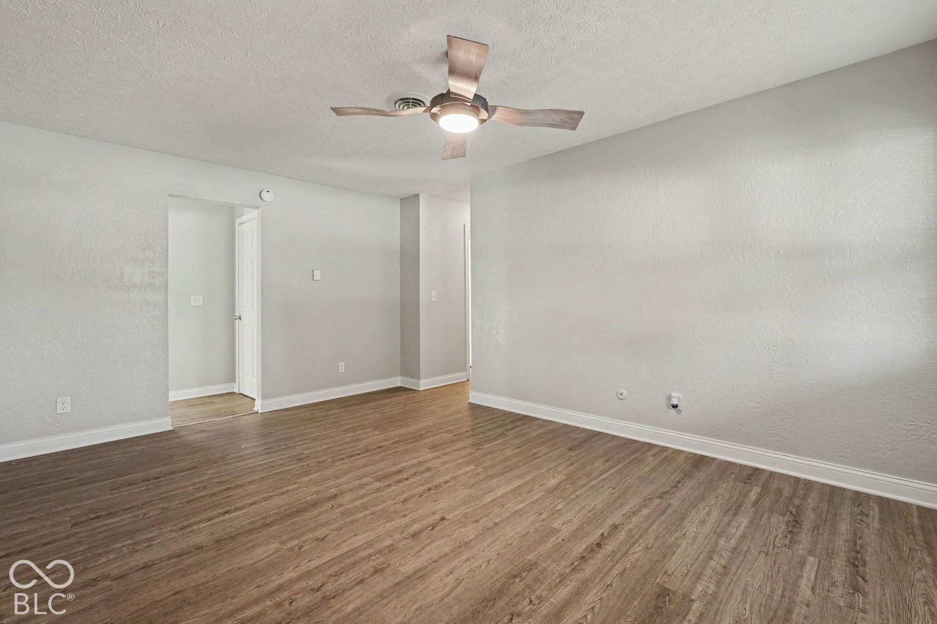 Wood-finish flooring, light-toned walls, and a ceiling fan with integrated lighting