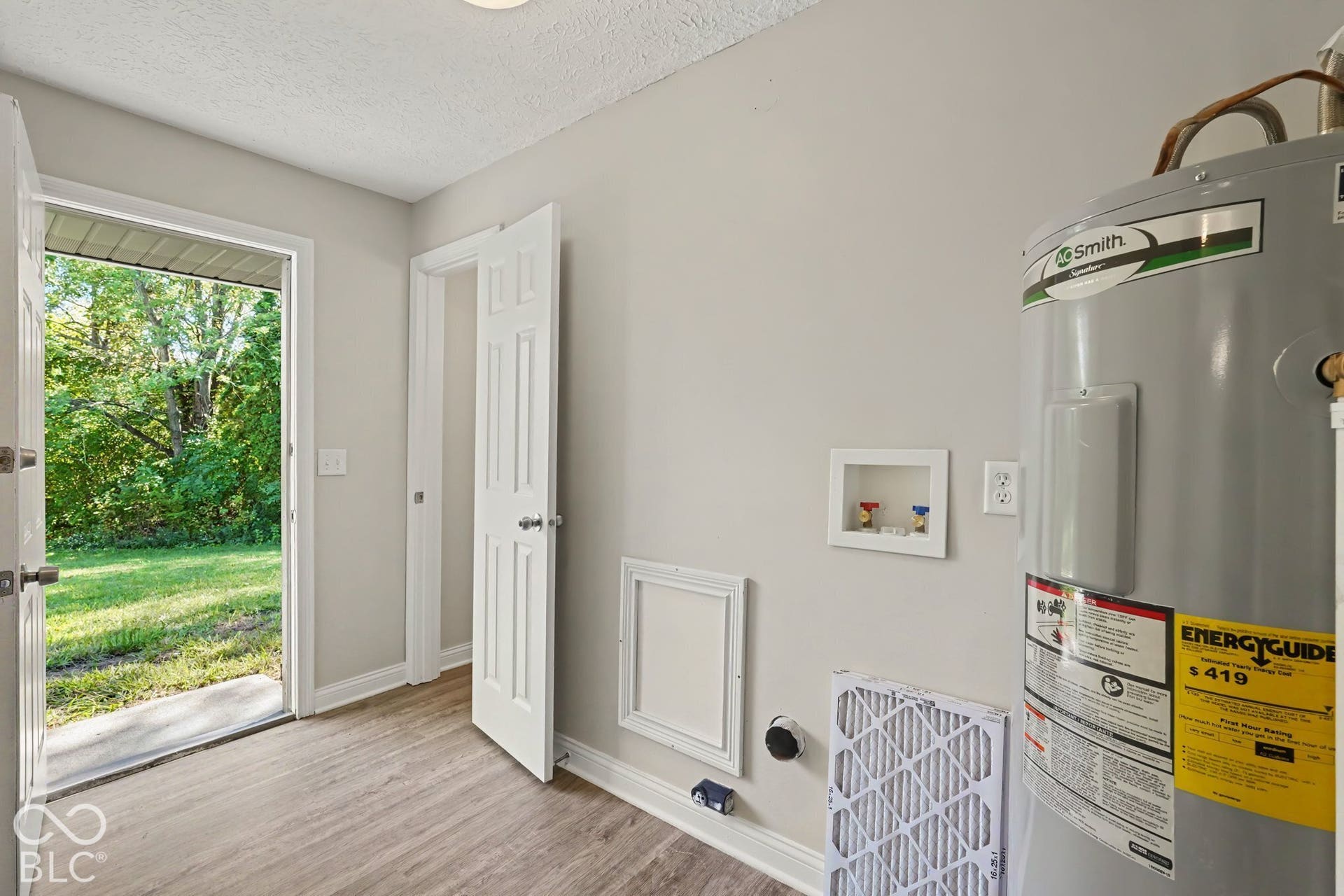 Utility space featuring a water heater, washer hookups, and wood-finish flooring