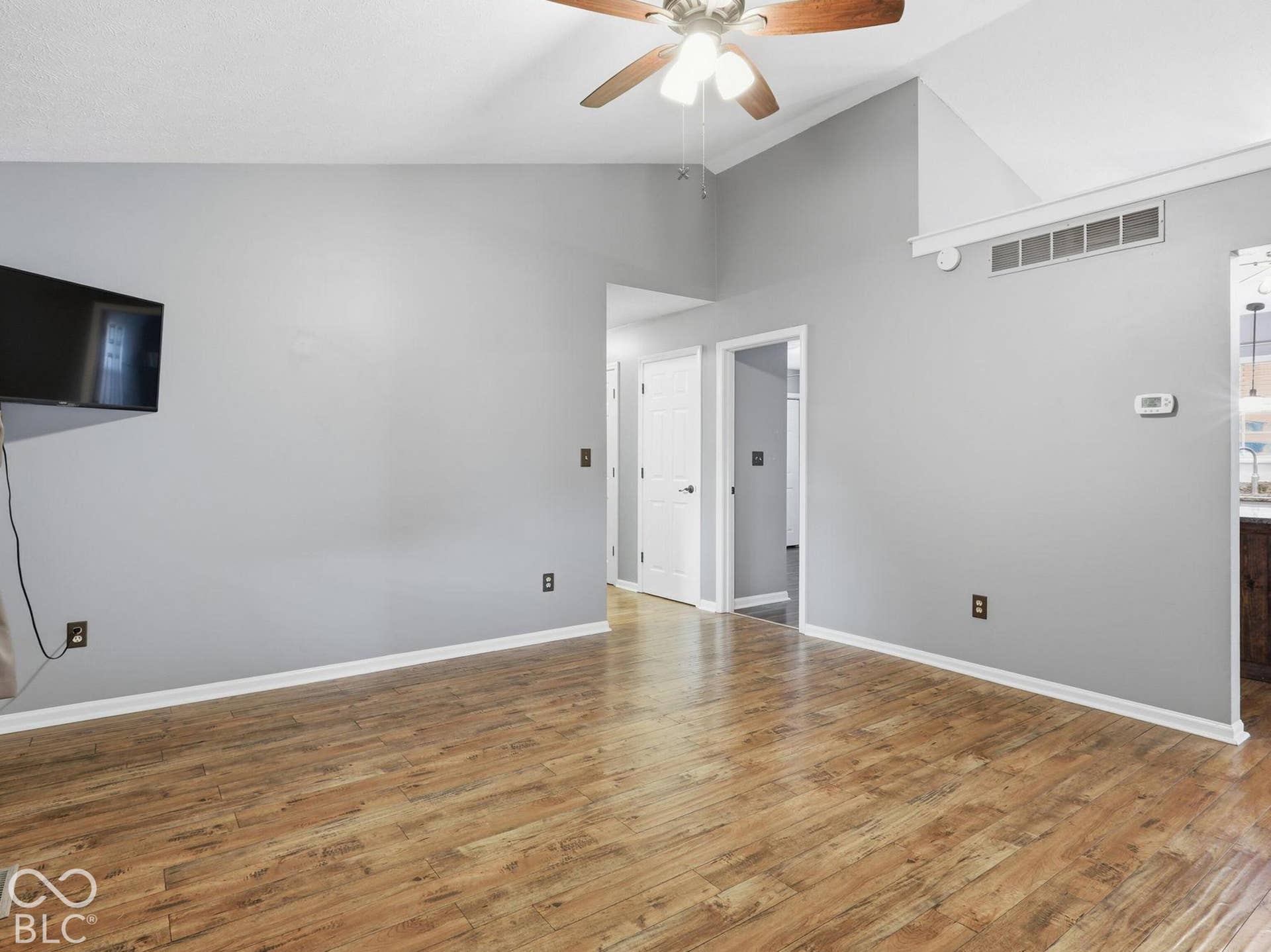 Cathedral ceilings, lighted ceiling fan and a mounted television adorn the room.
