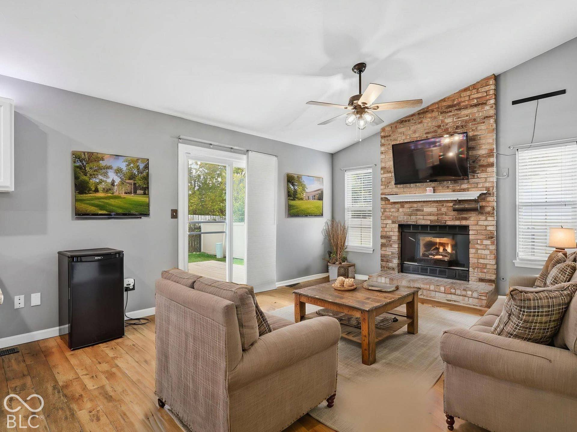The family room has a wood burning fireplace insert, a mounted TV, and sliders to the back yard