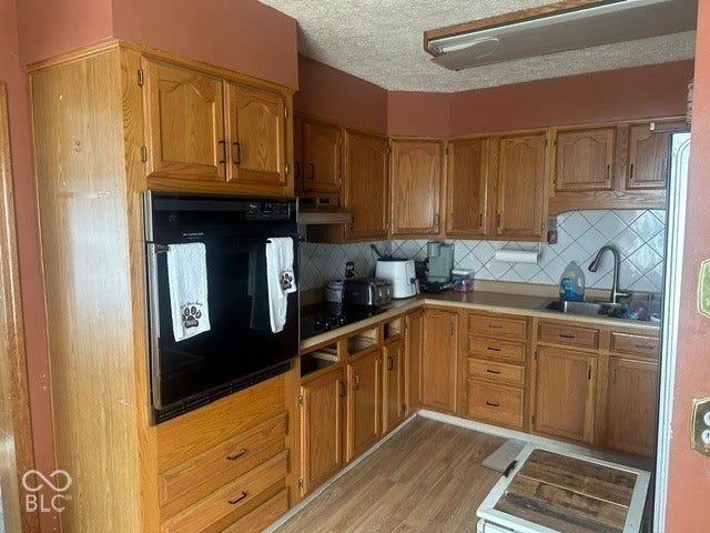 1832 Bauer, Indianapolis, IN 46218 Kitchen featuring wood cabinetry, integrated wall oven, cooktop, diagonal tile backsplash, and stainless steel sink with pull-down faucet