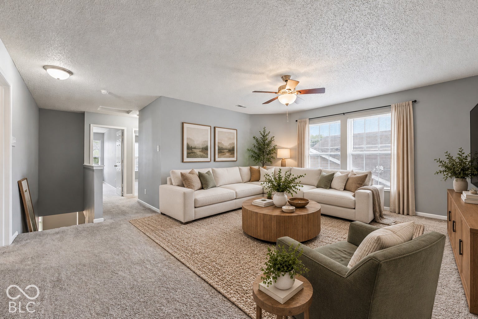 Virtually Altered - Neutral-toned living space featuring wall-to-wall carpeting, an integrated ceiling fan with light fixture, and multiple windows