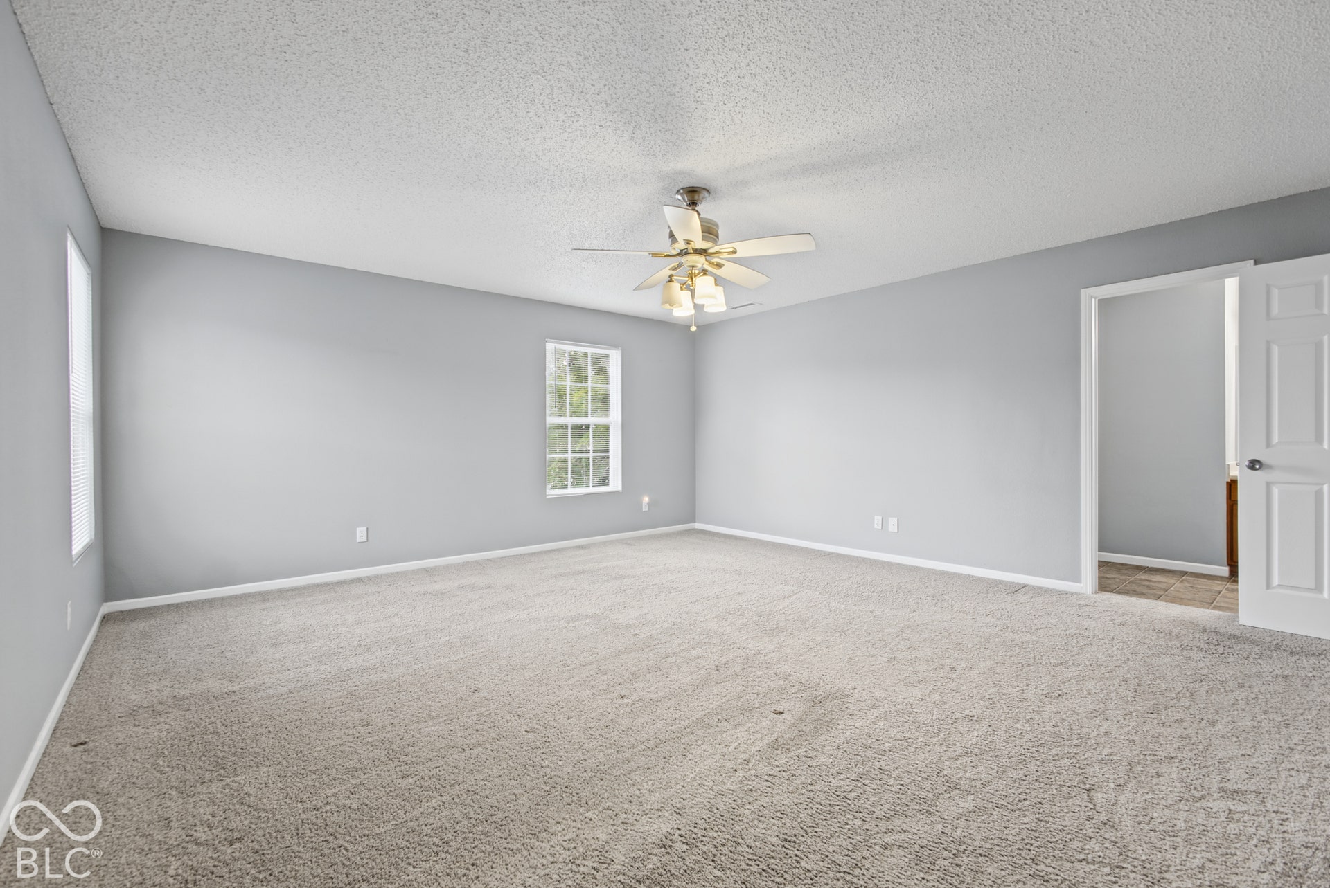 Neutral-toned walls, wall-to-wall carpeting, ceiling fan with integrated lighting, and multi-pane windows