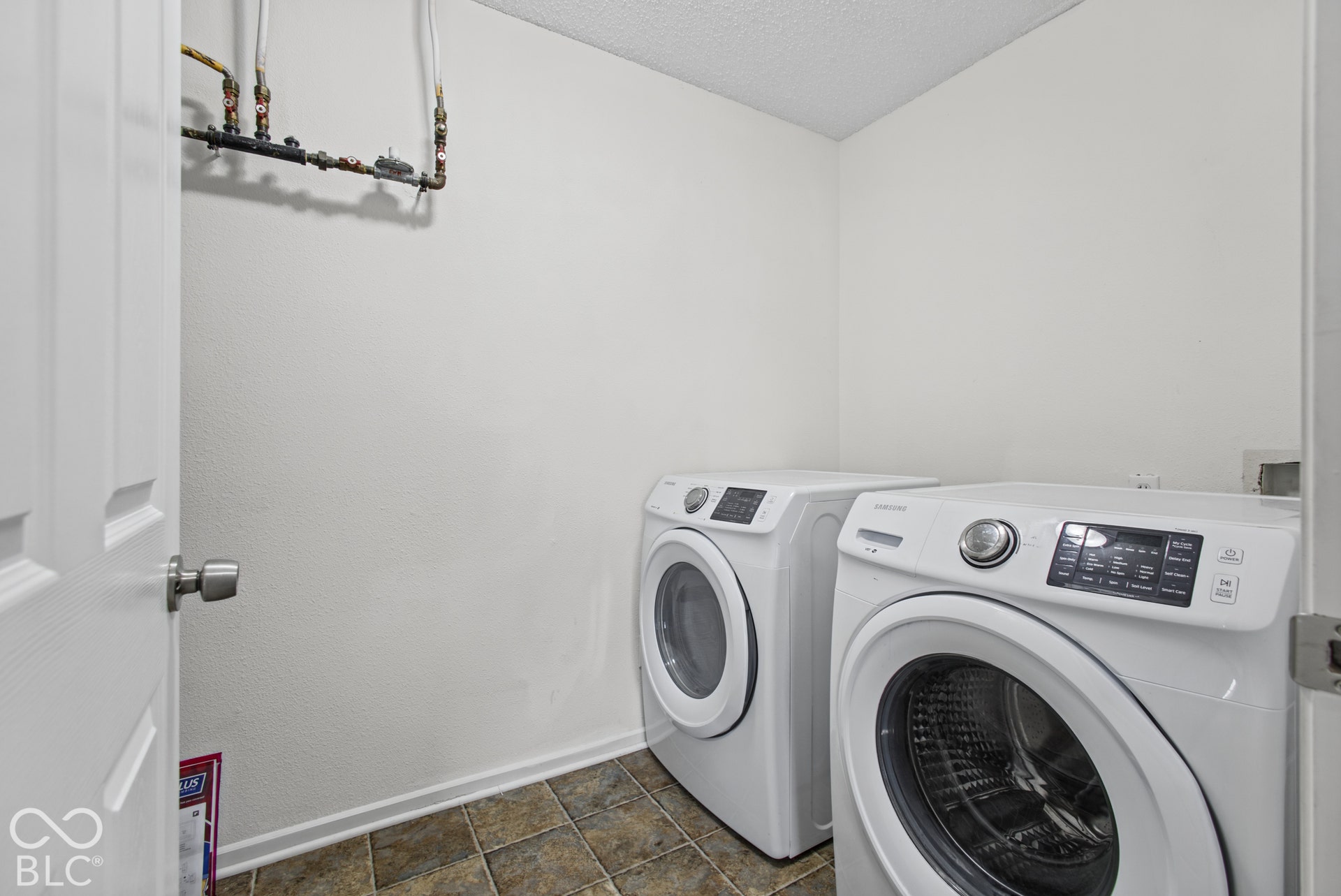 Laundry area featuring tile flooring and exposed plumbing