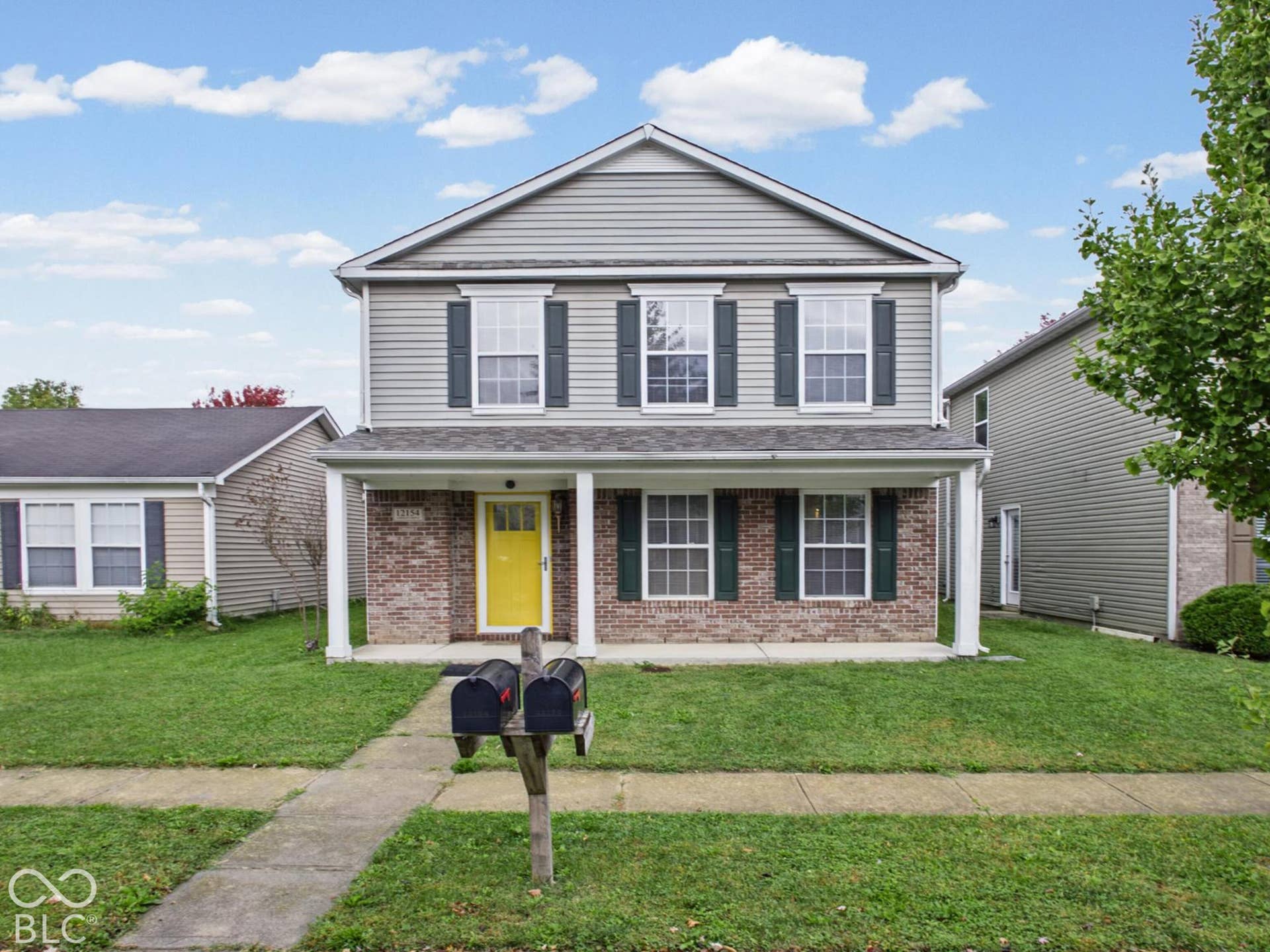 Two-story residence featuring a brick and horizontal siding exterior, a covered front porch with white columns, and decorative window shutters