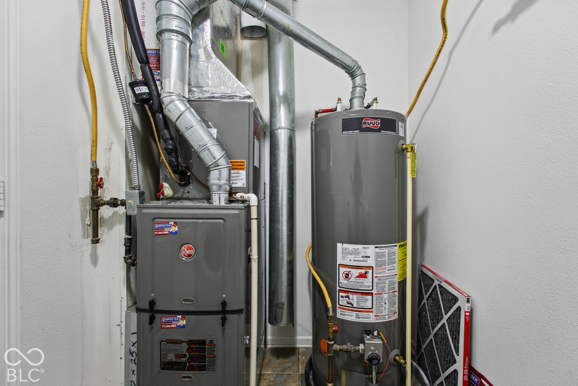Mechanical utility closet featuring a Rheem furnace, metal ventilation ducting, and a residential water heater