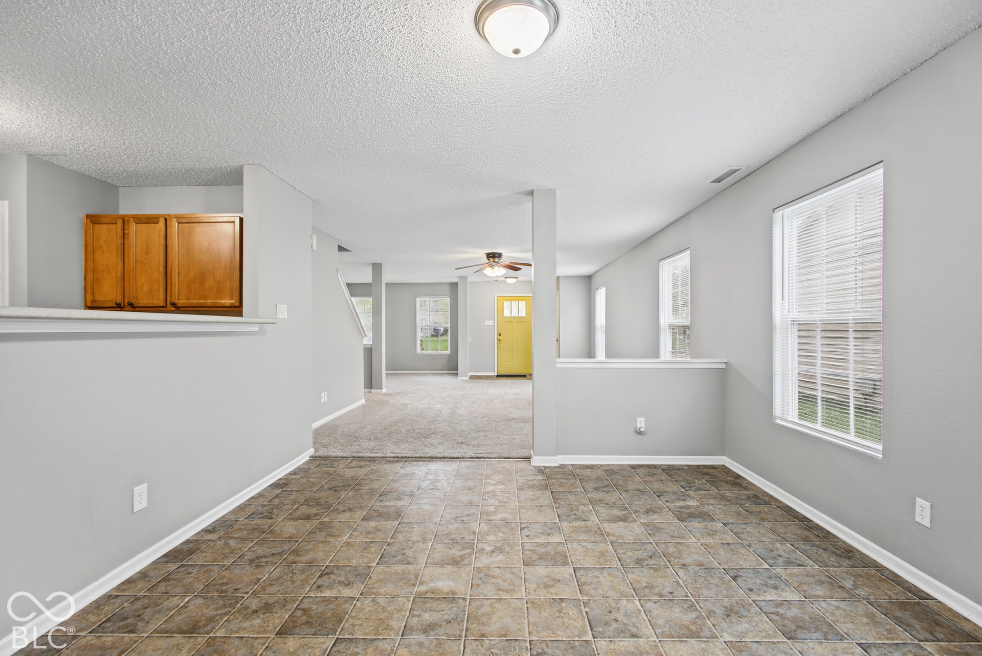 Open interior featuring neutral wall paint, tiled flooring, built-in upper cabinetry, ceiling fan, and multi-paned exterior door