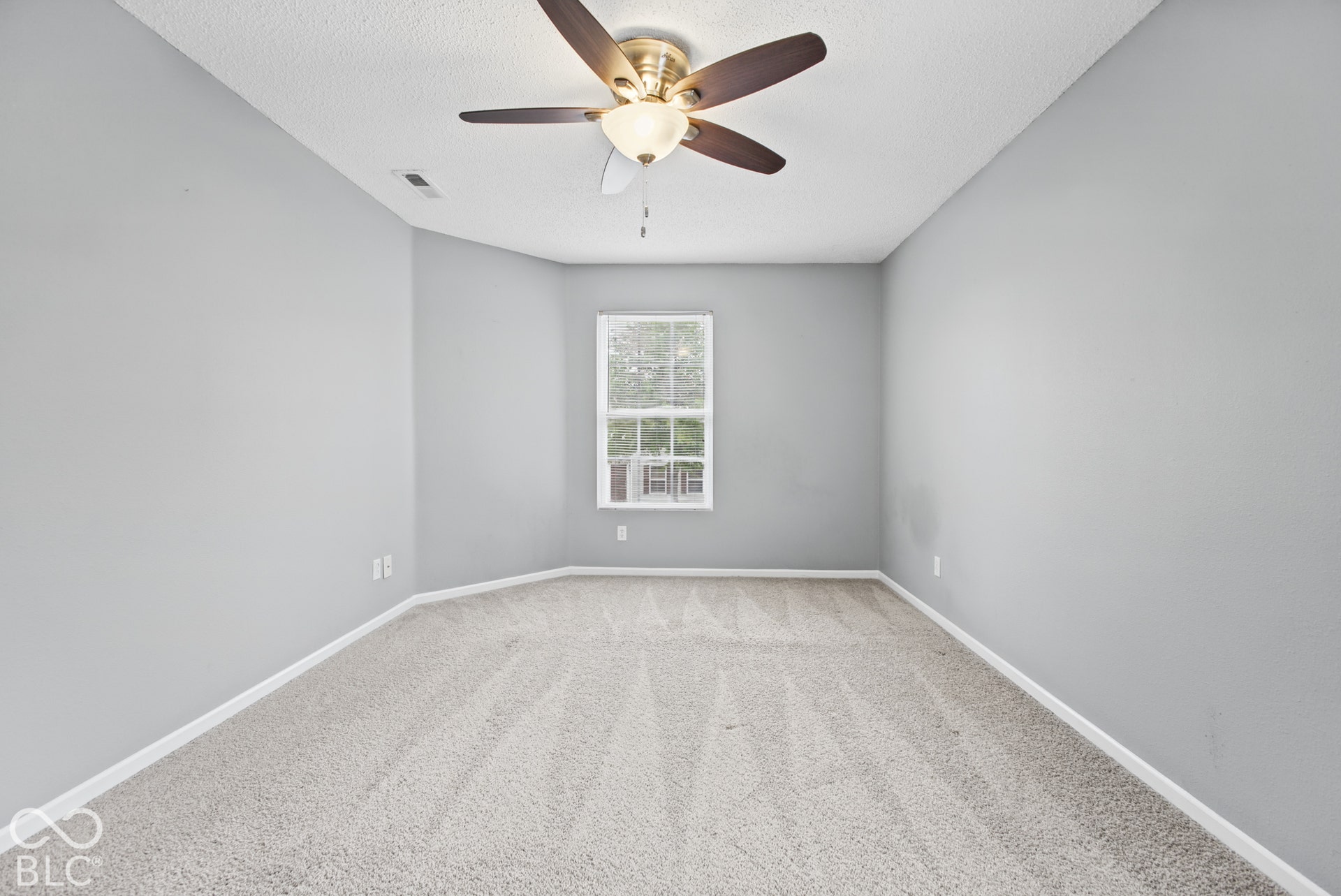 Neutral-toned interior featuring wall-to-wall carpeting, a multi-pane window, and a ceiling fan with integrated light fixture